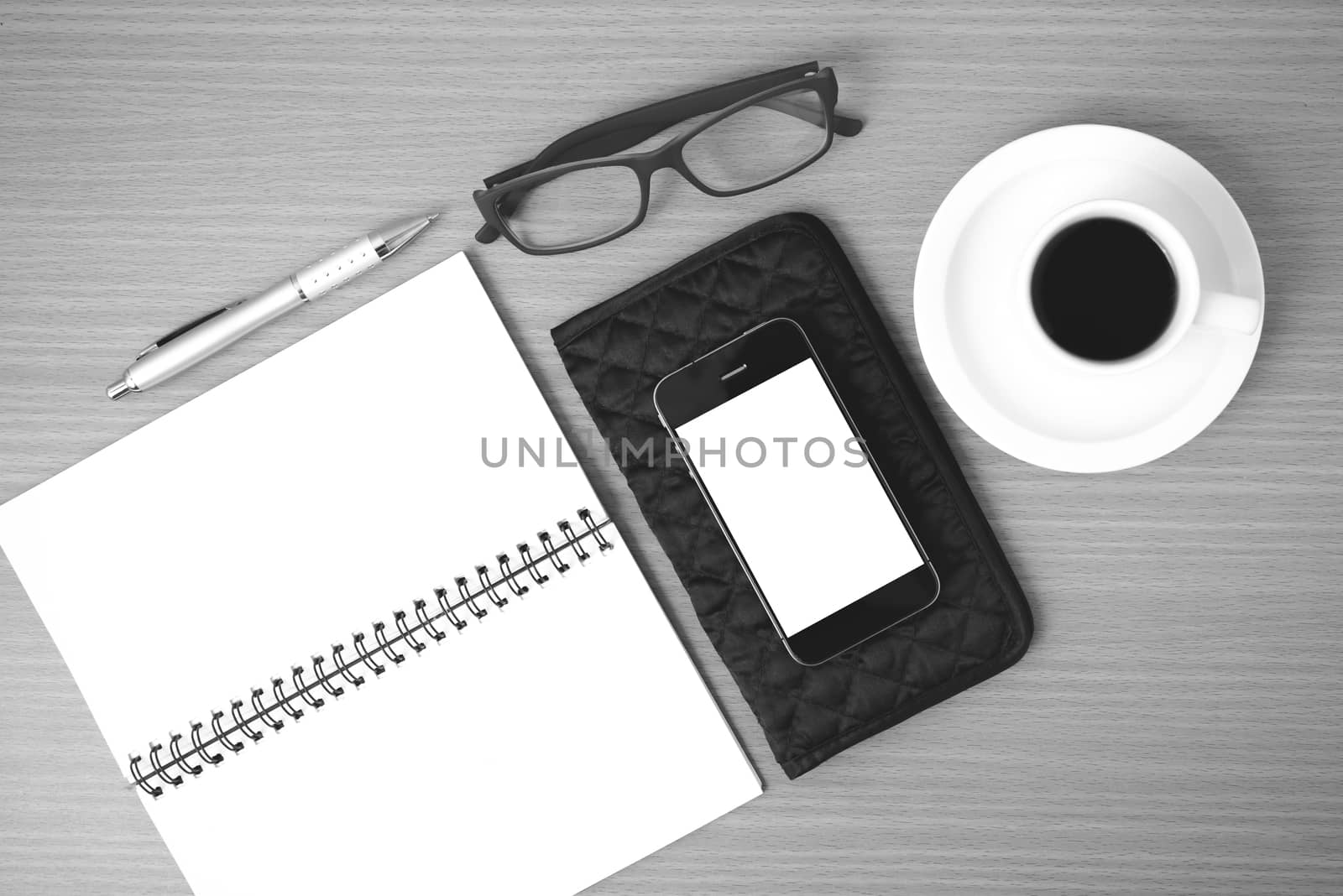 coffee,phone,eyeglasses,notepad and wallet on wood table background black and white color