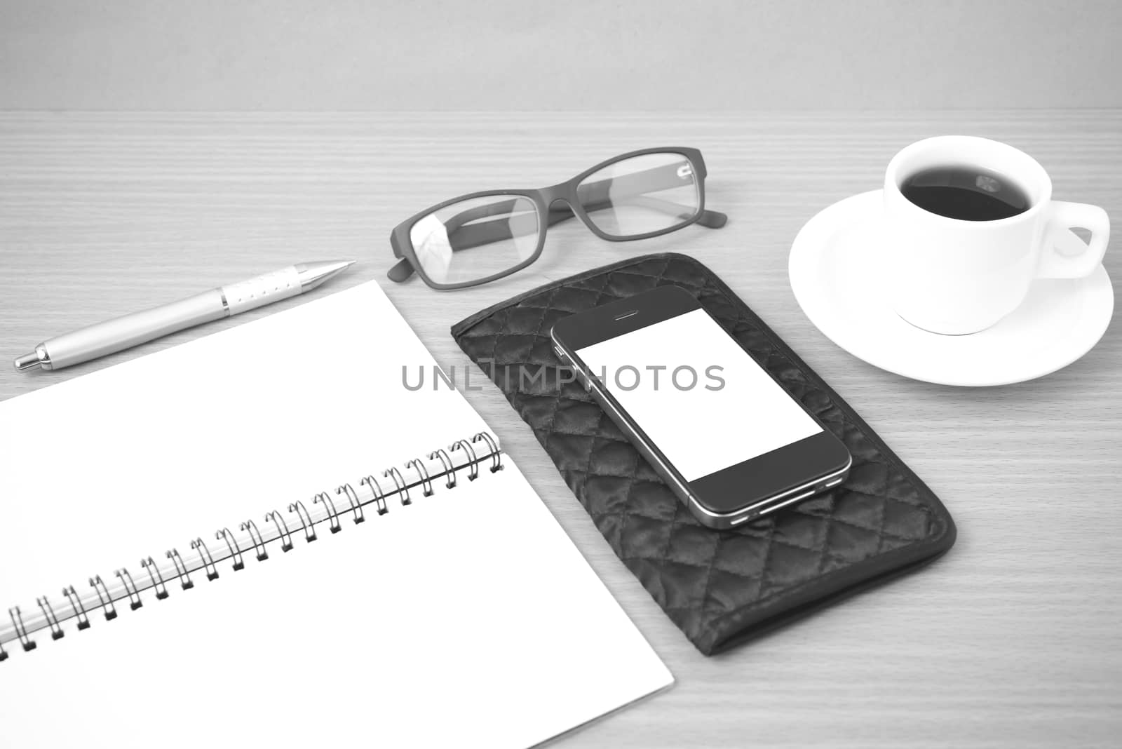 coffee,phone,eyeglasses,notepad and wallet on wood table background black and white color