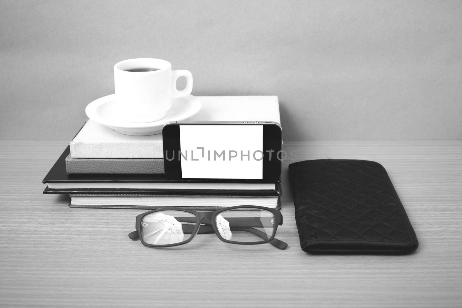 coffee,phone,eyeglasses,stack of book and wallet on wood table background black and white color