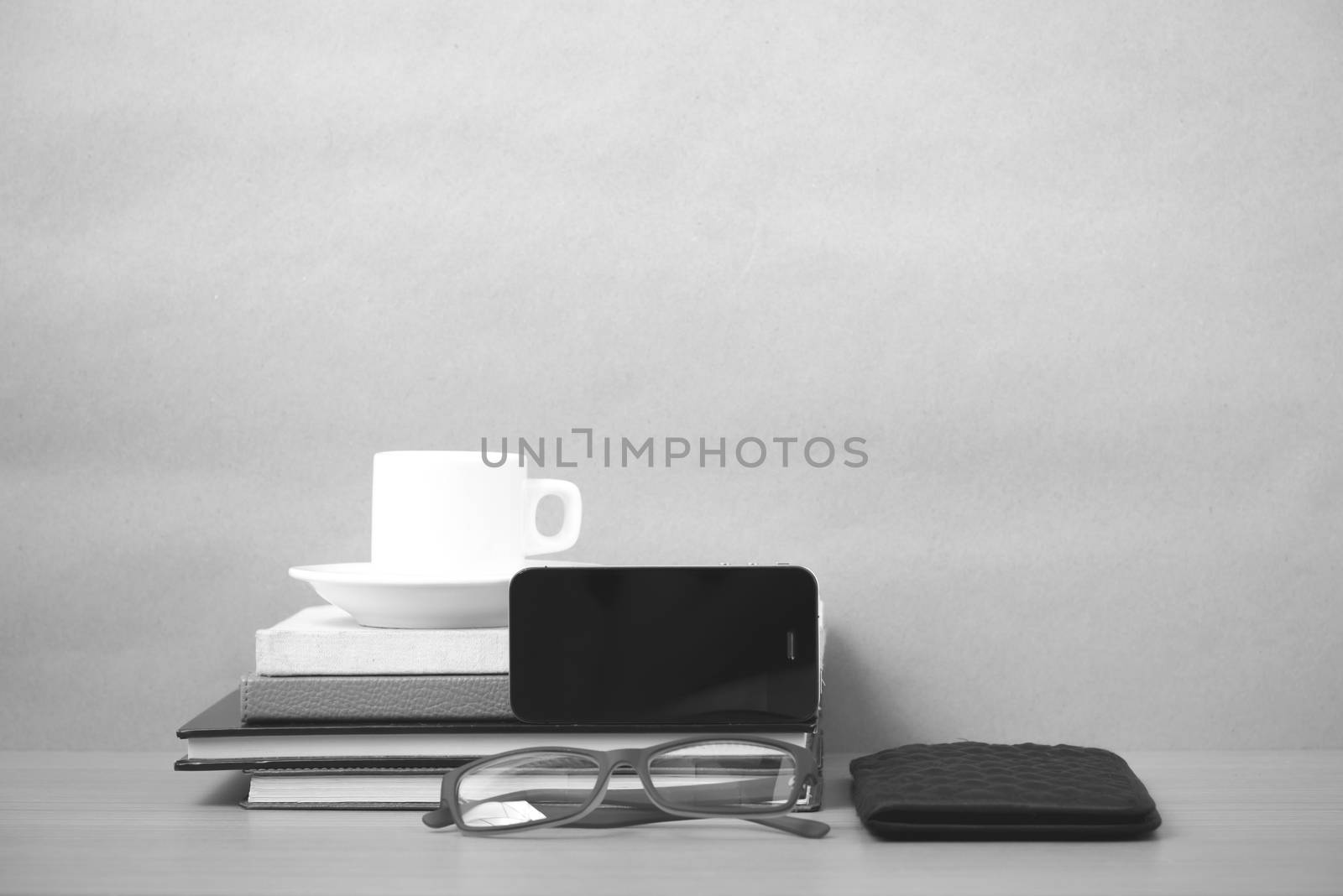 coffee,phone,eyeglasses,stack of book and wallet on wood table background black and white color