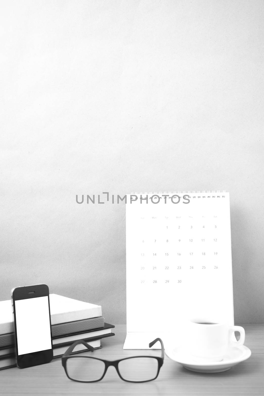coffee,phone,eyeglasses,stack of book and calendar on wood table background black and white color