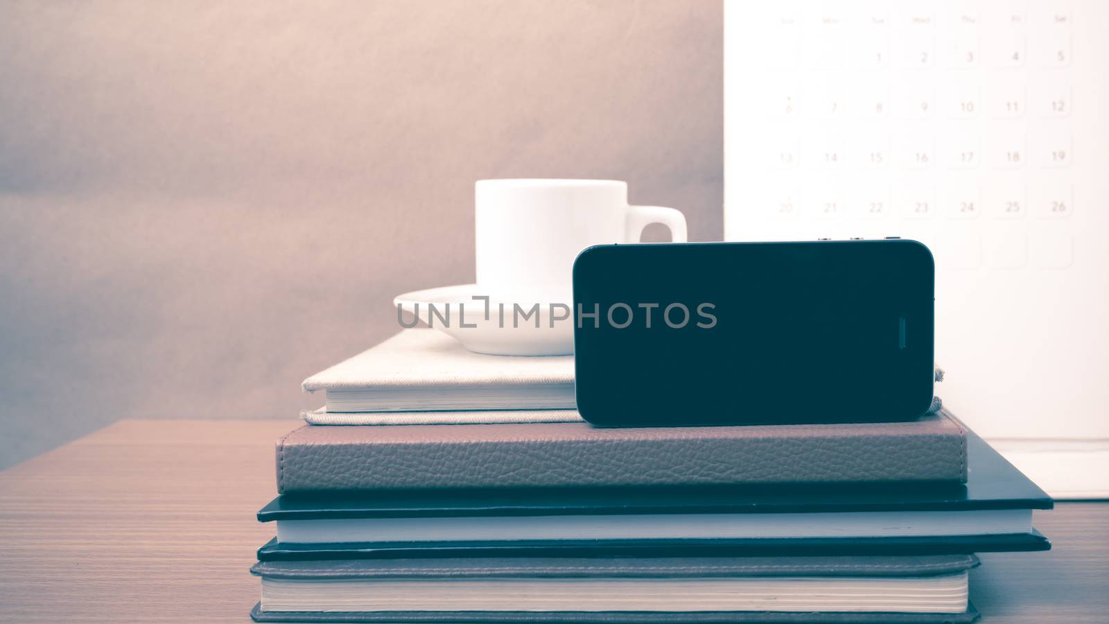 coffee,phone,stack of book and calendar on wood table background vintage style