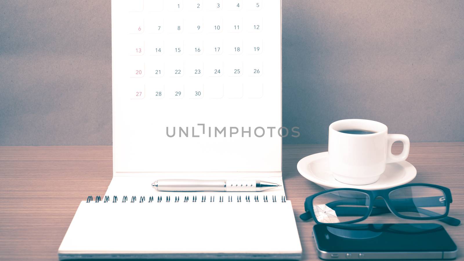 coffee,phone,eyeglasses,notepad and canlendar on wood table background vintage style