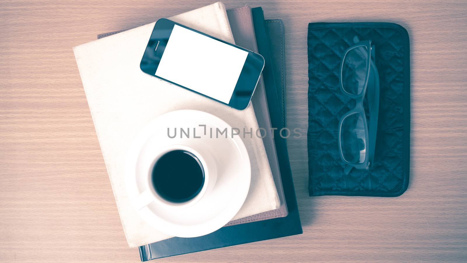 coffee,phone,eyeglasses,stack of book and wallet on wood table background vintage style