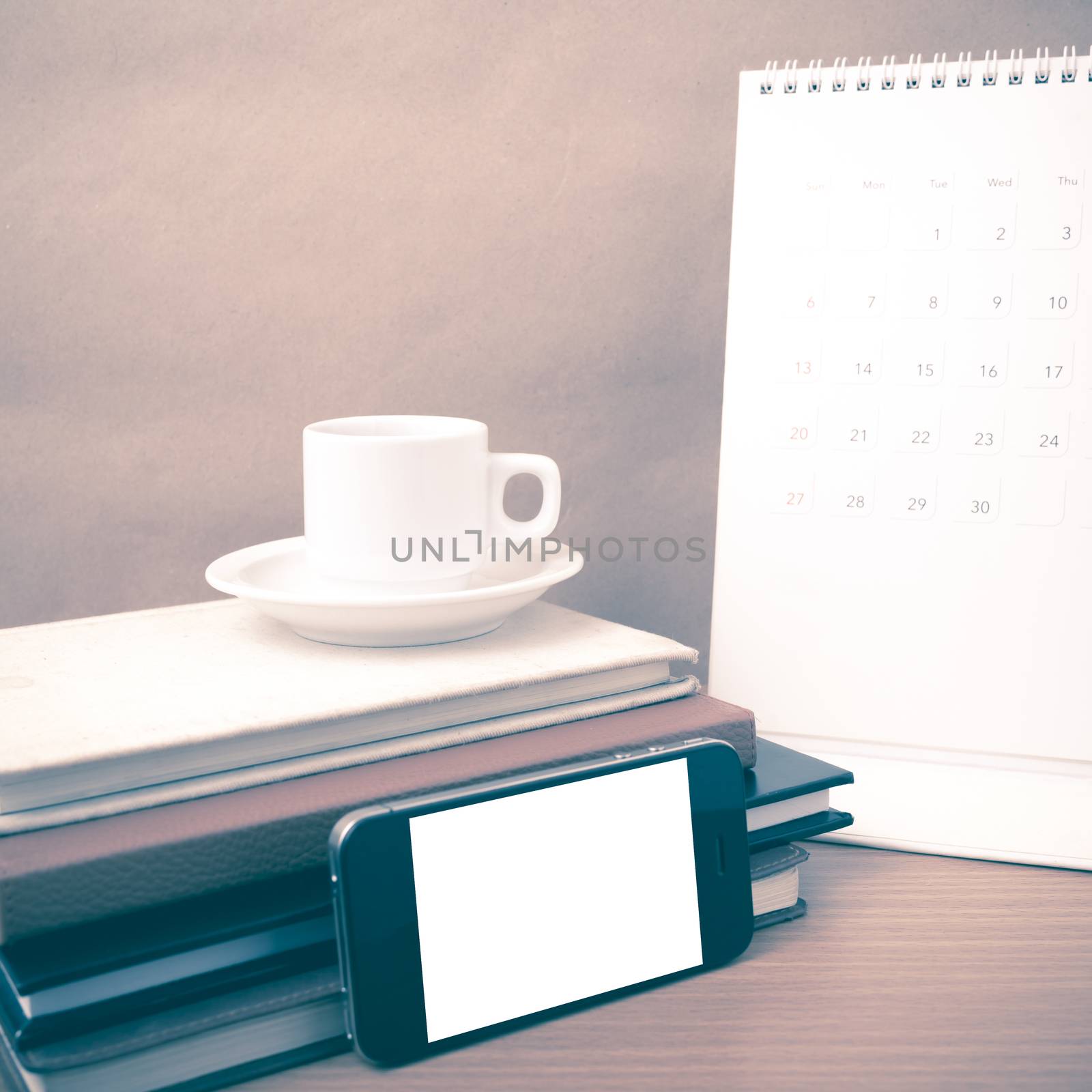 coffee,phone,stack of book and calendar on wood table background vintage style