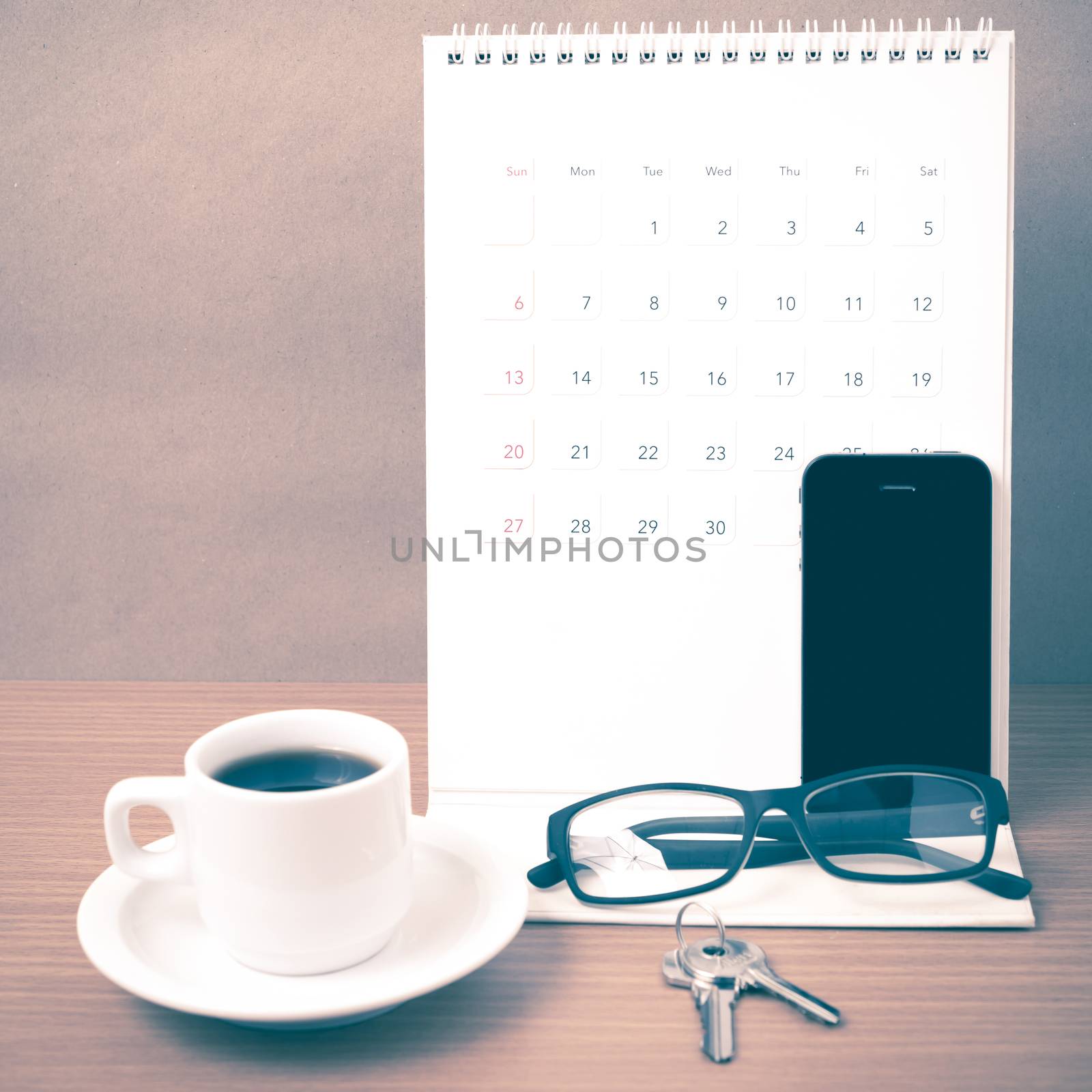 coffee,phone,eyeglasses,calendar and key on wood table background vintage style