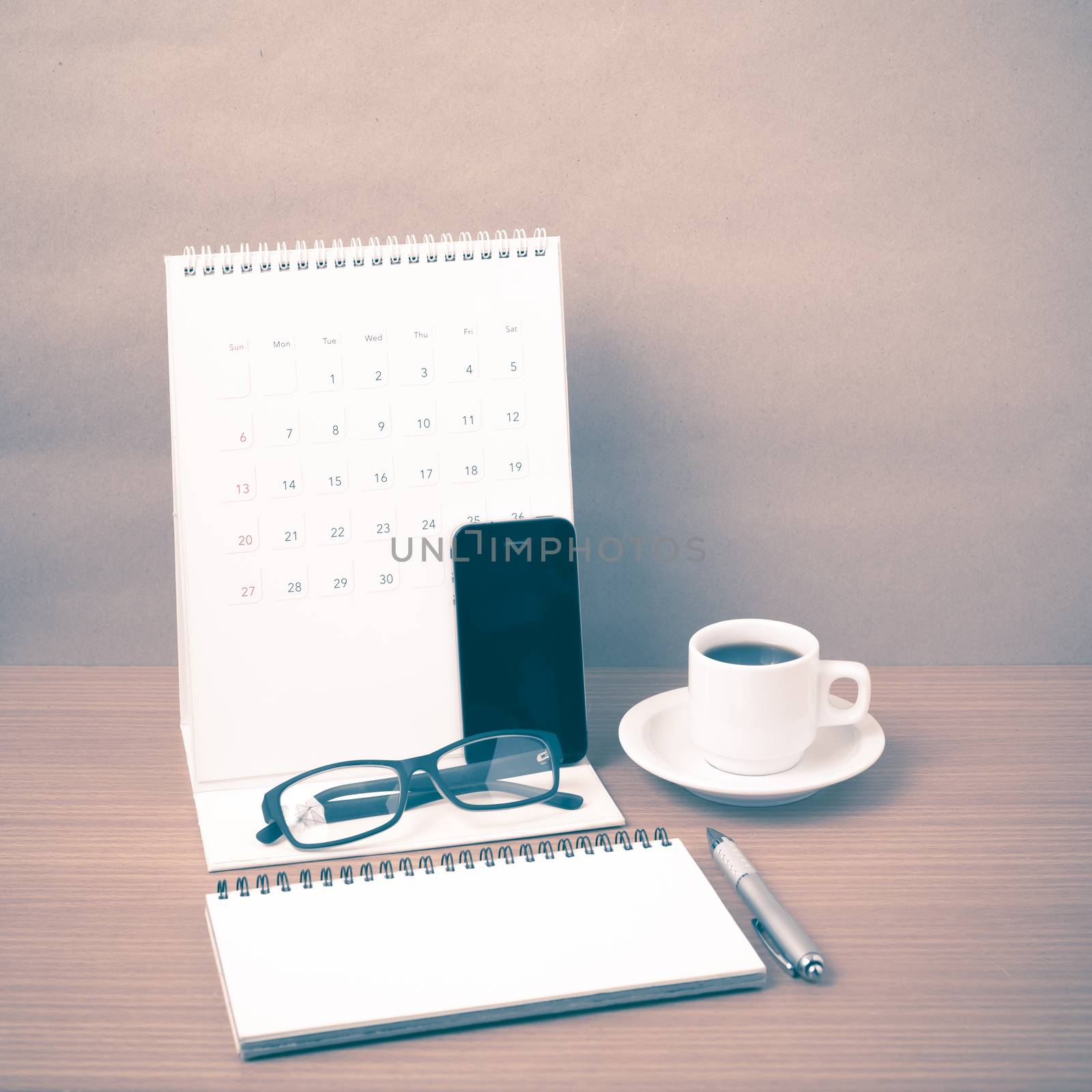 coffee,phone,eyeglasses,notepad and canlendar on wood table background vintage style