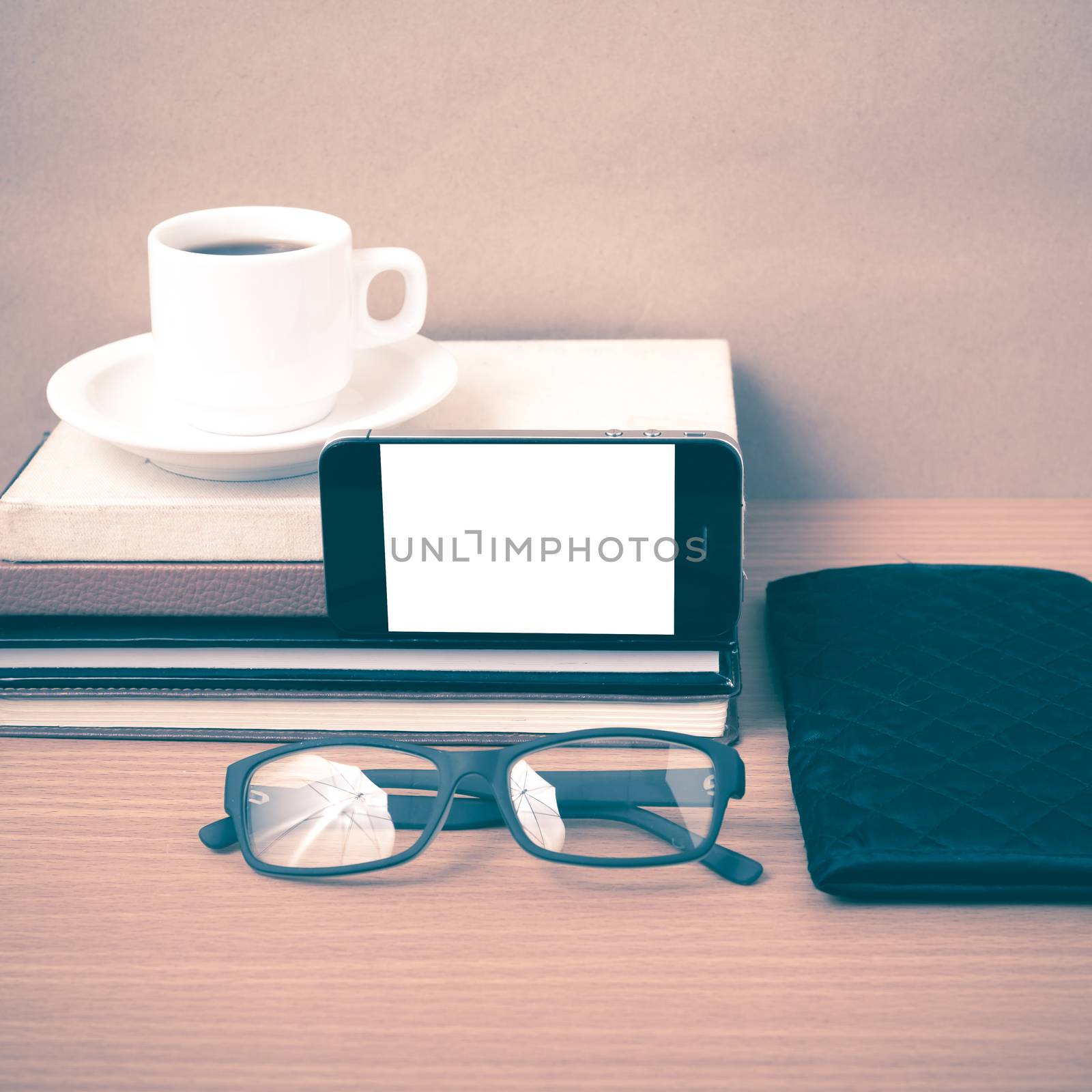 coffee,phone,eyeglasses,stack of book and wallet on wood table background vintage style