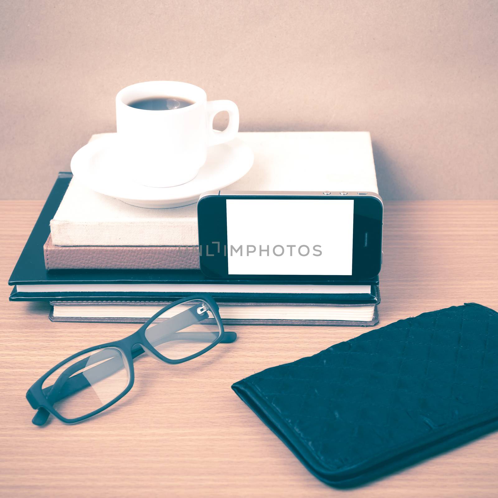 coffee,phone,eyeglasses,stack of book and wallet on wood table background vintage style