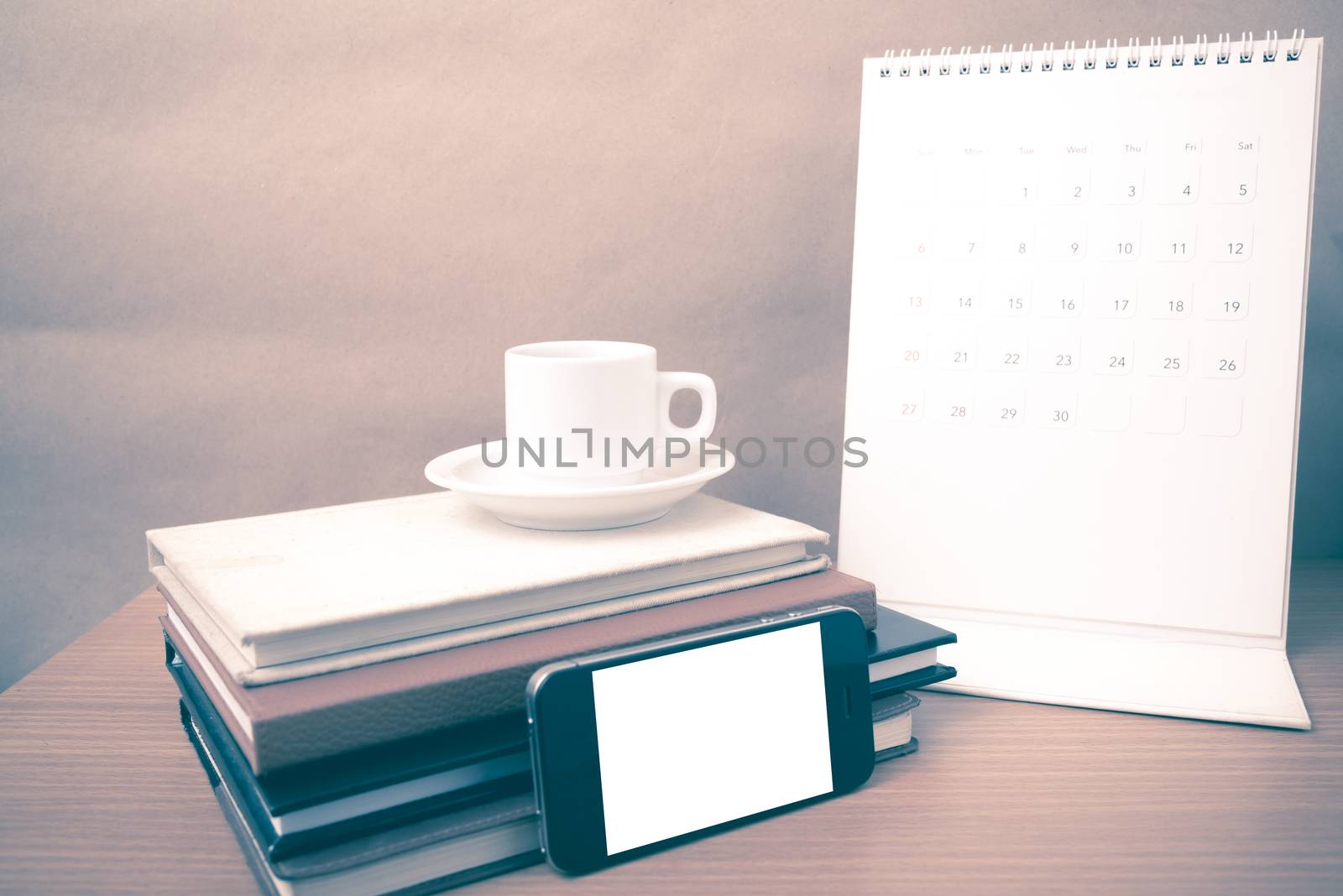 coffee,phone,stack of book and calendar on wood table background vintage style