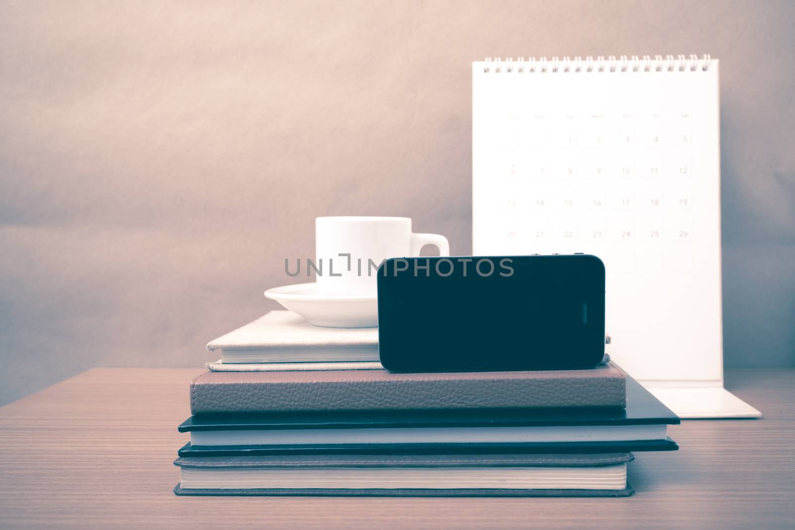 coffee,phone,stack of book and calendar on wood table background vintage style