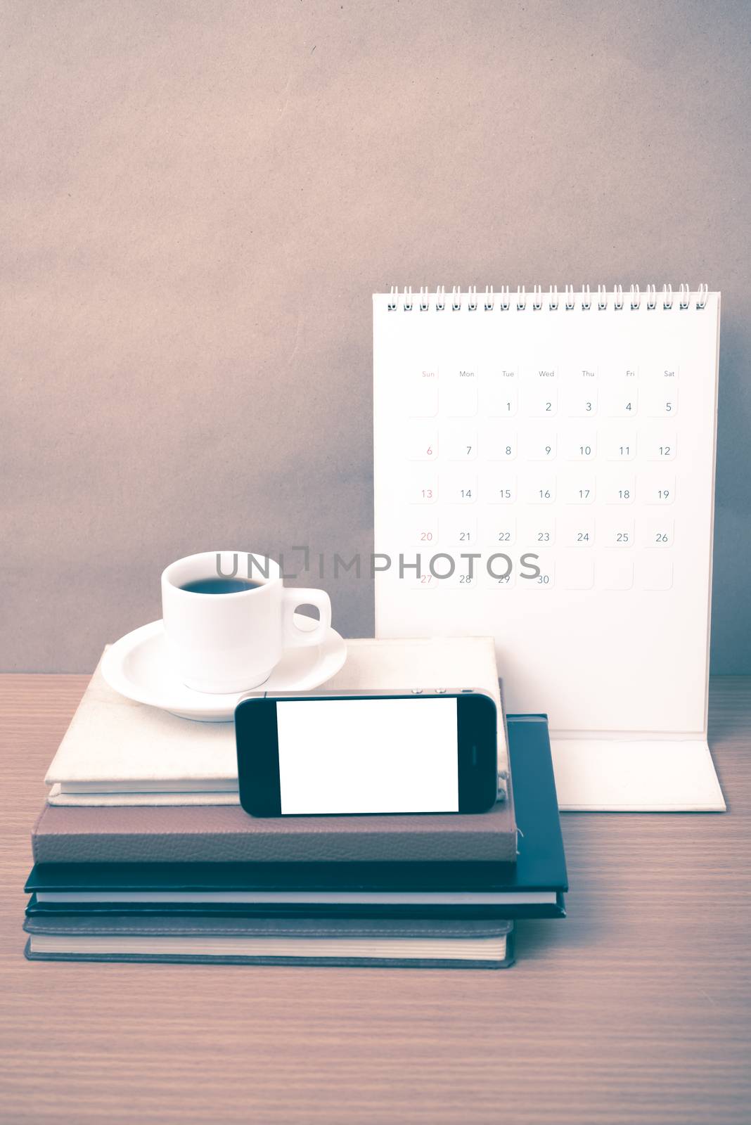 coffee,phone,stack of book and calendar on wood table background vintage style