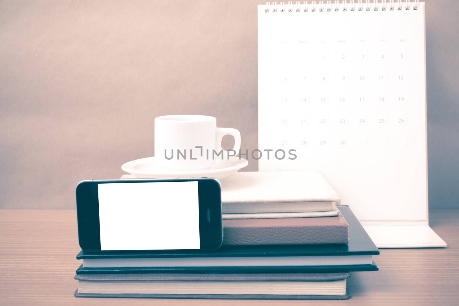 coffee,phone,stack of book and calendar on wood table background vintage style