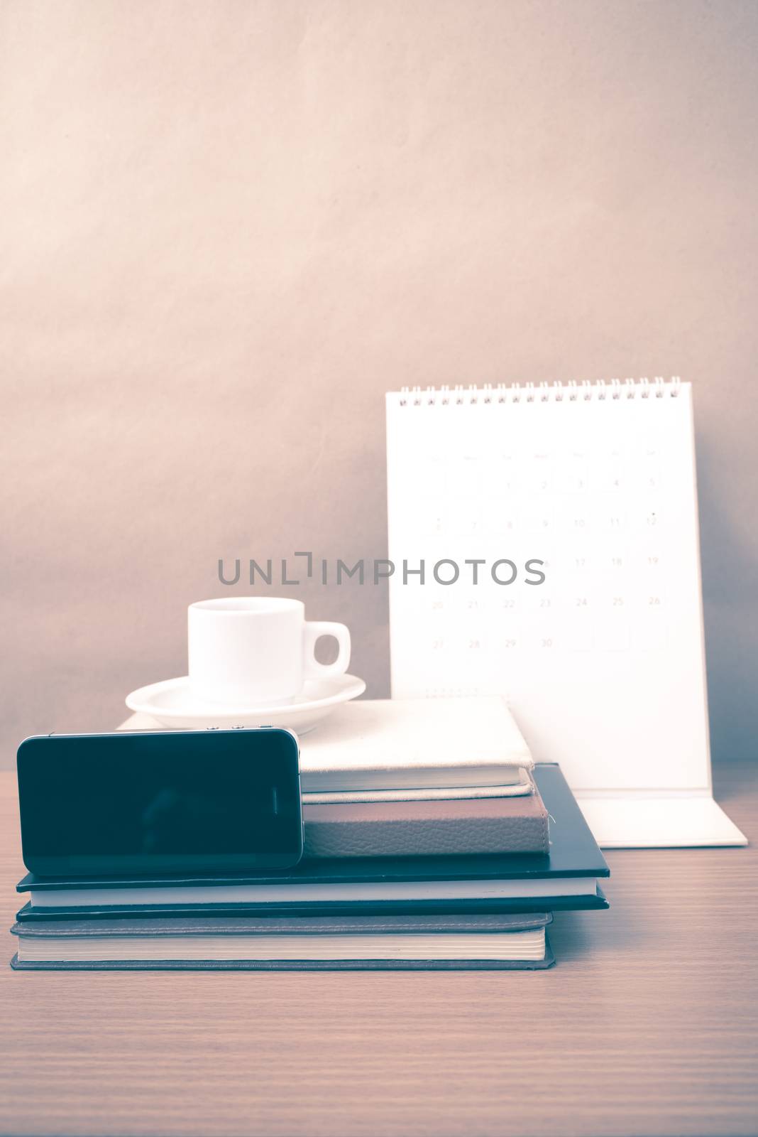 coffee,phone,stack of book and calendar on wood table background vintage style