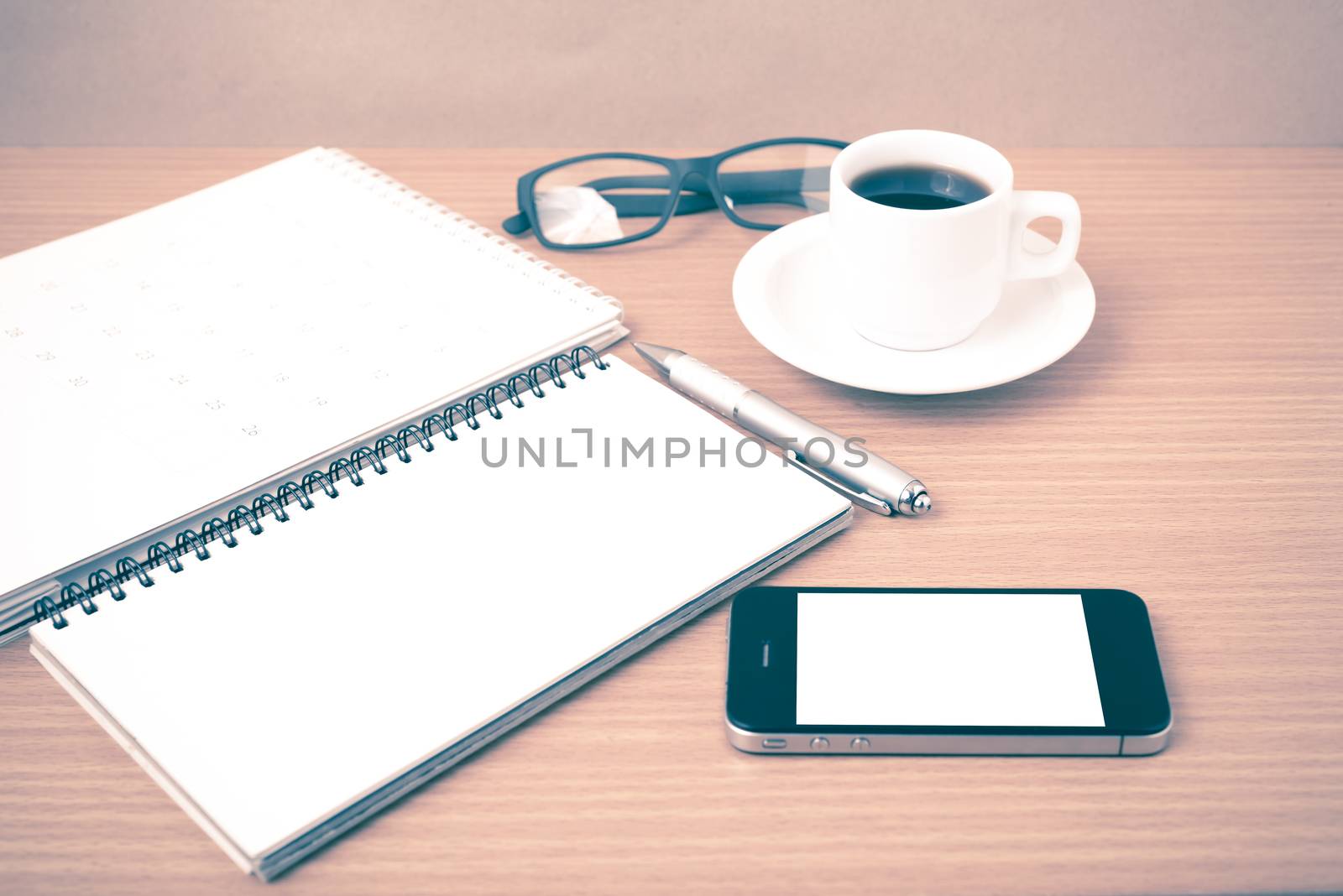 coffee,phone,eyeglasses,notepad and canlendar on wood table background vintage style