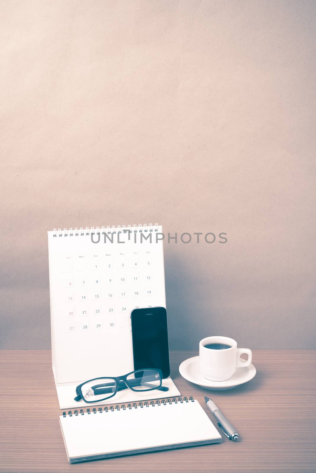 coffee,phone,eyeglasses,notepad and canlendar on wood table background vintage style