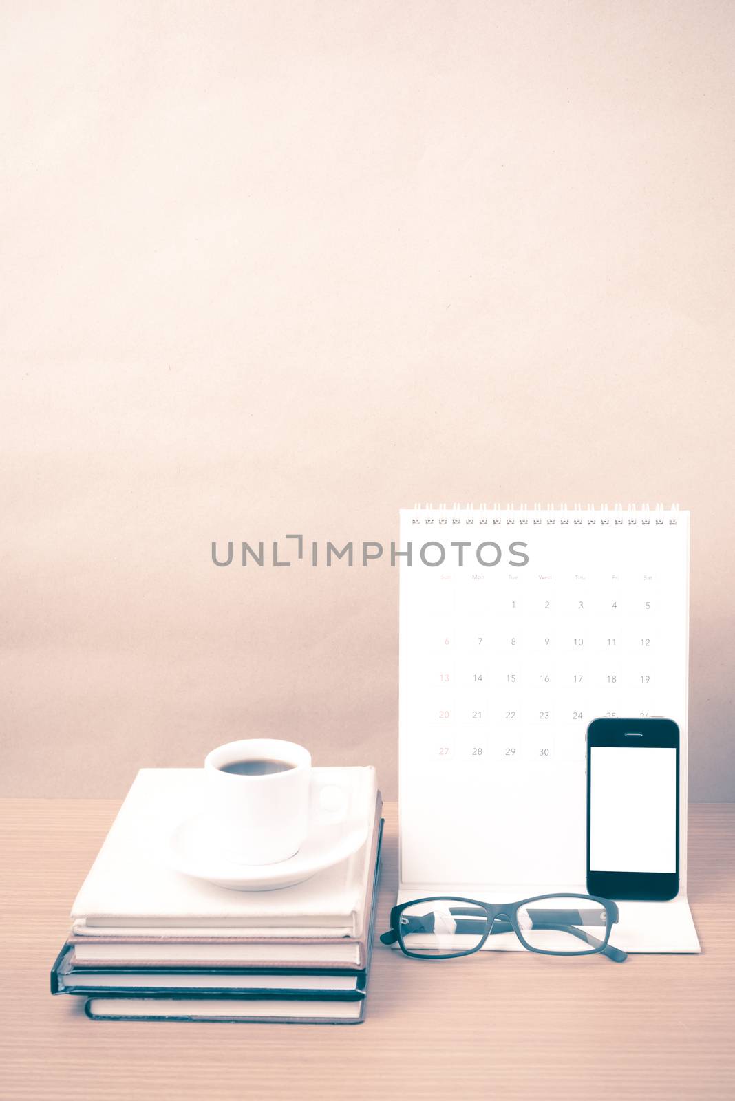 coffee,phone,eyeglasses,stack of book and calendar on wood table background vintage style