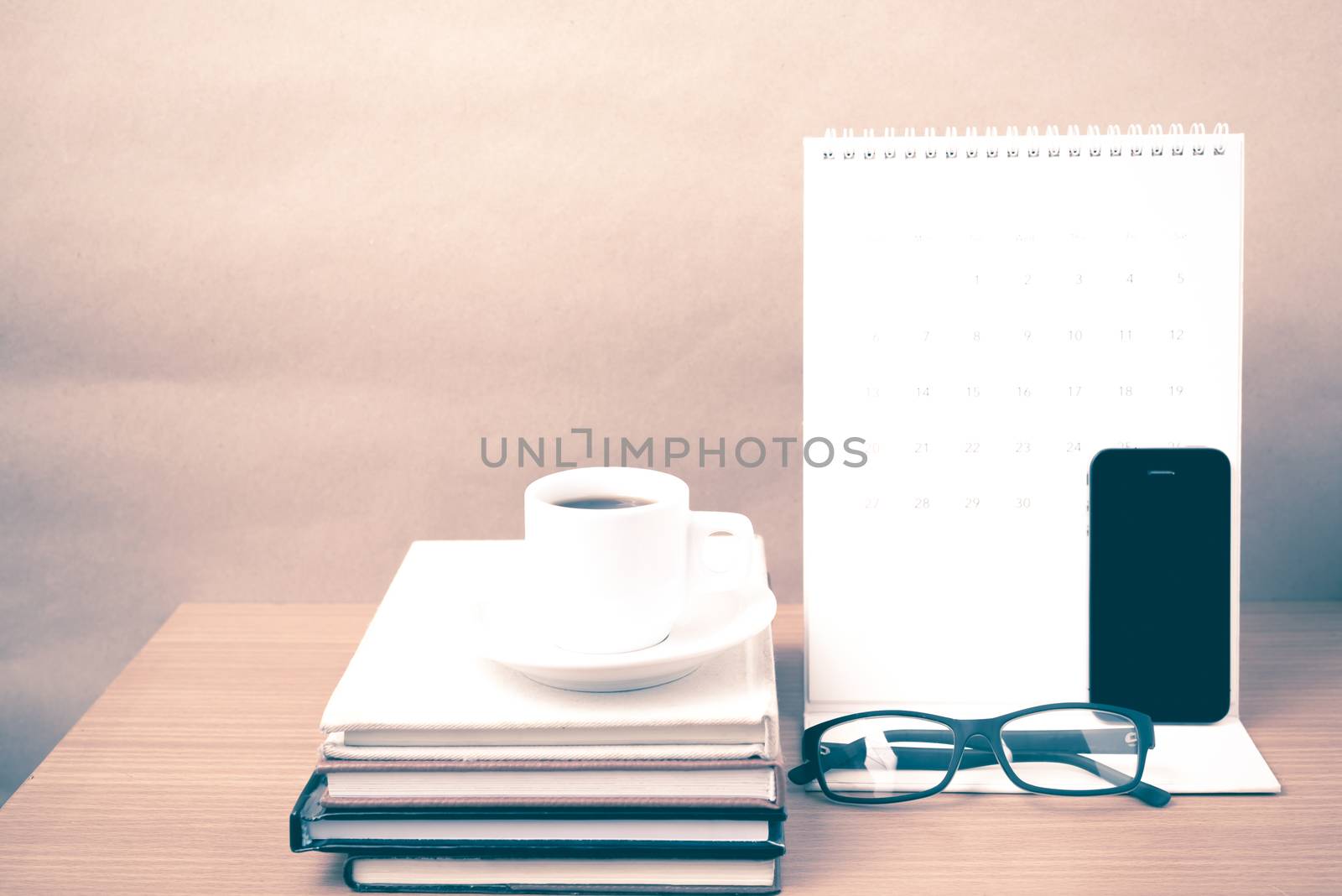 coffee,phone,eyeglasses,stack of book and calendar on wood table background vintage style