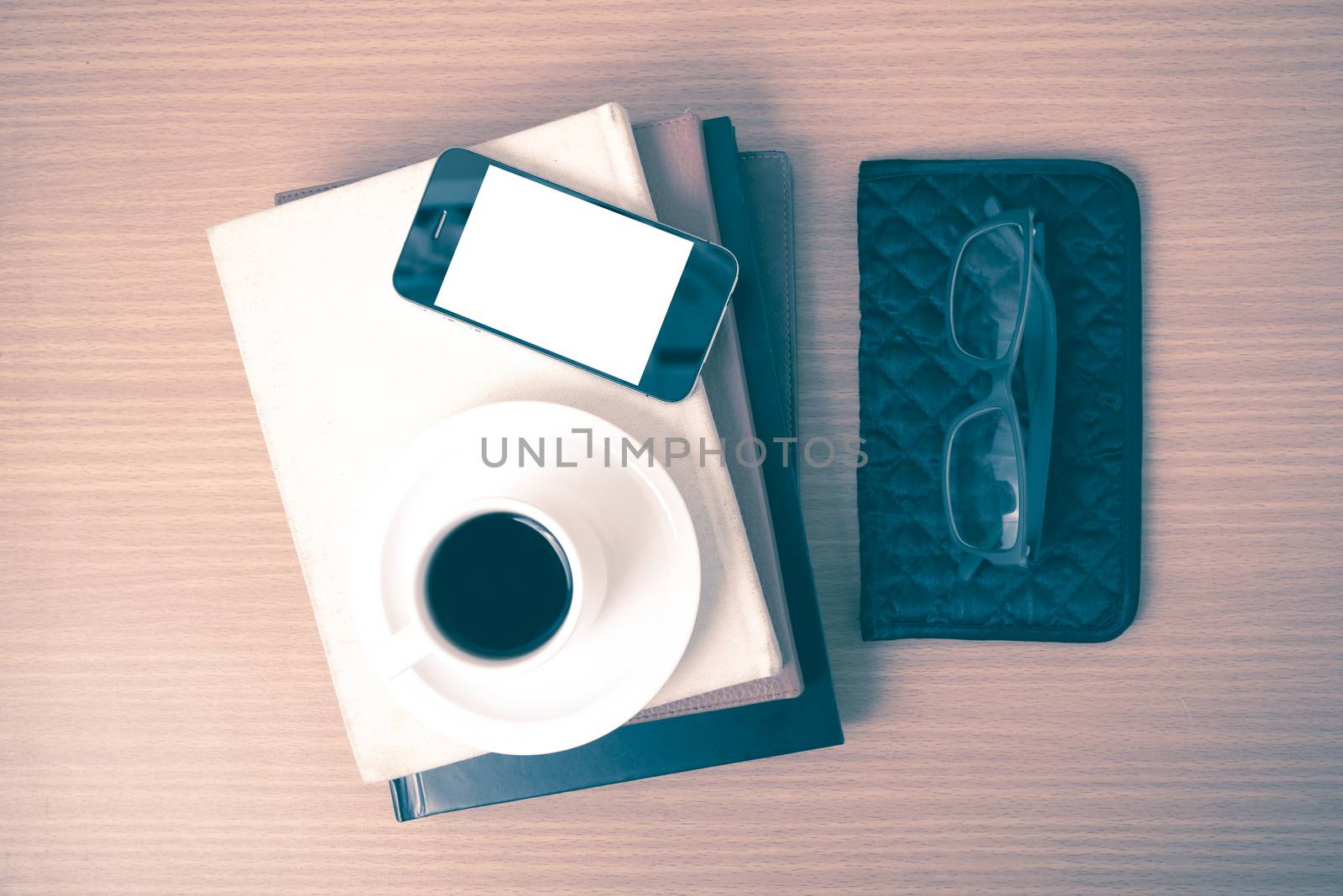 coffee,phone,eyeglasses,stack of book and wallet on wood table background vintage style