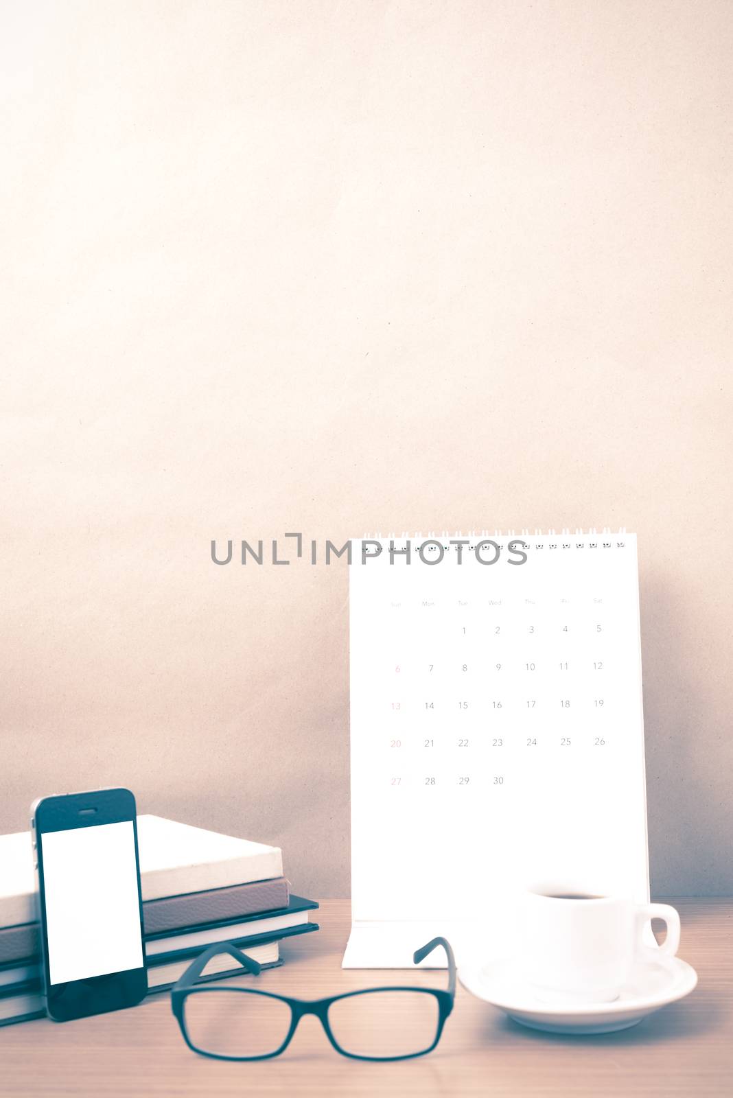 coffee,phone,eyeglasses,stack of book and calendar on wood table background vintage style