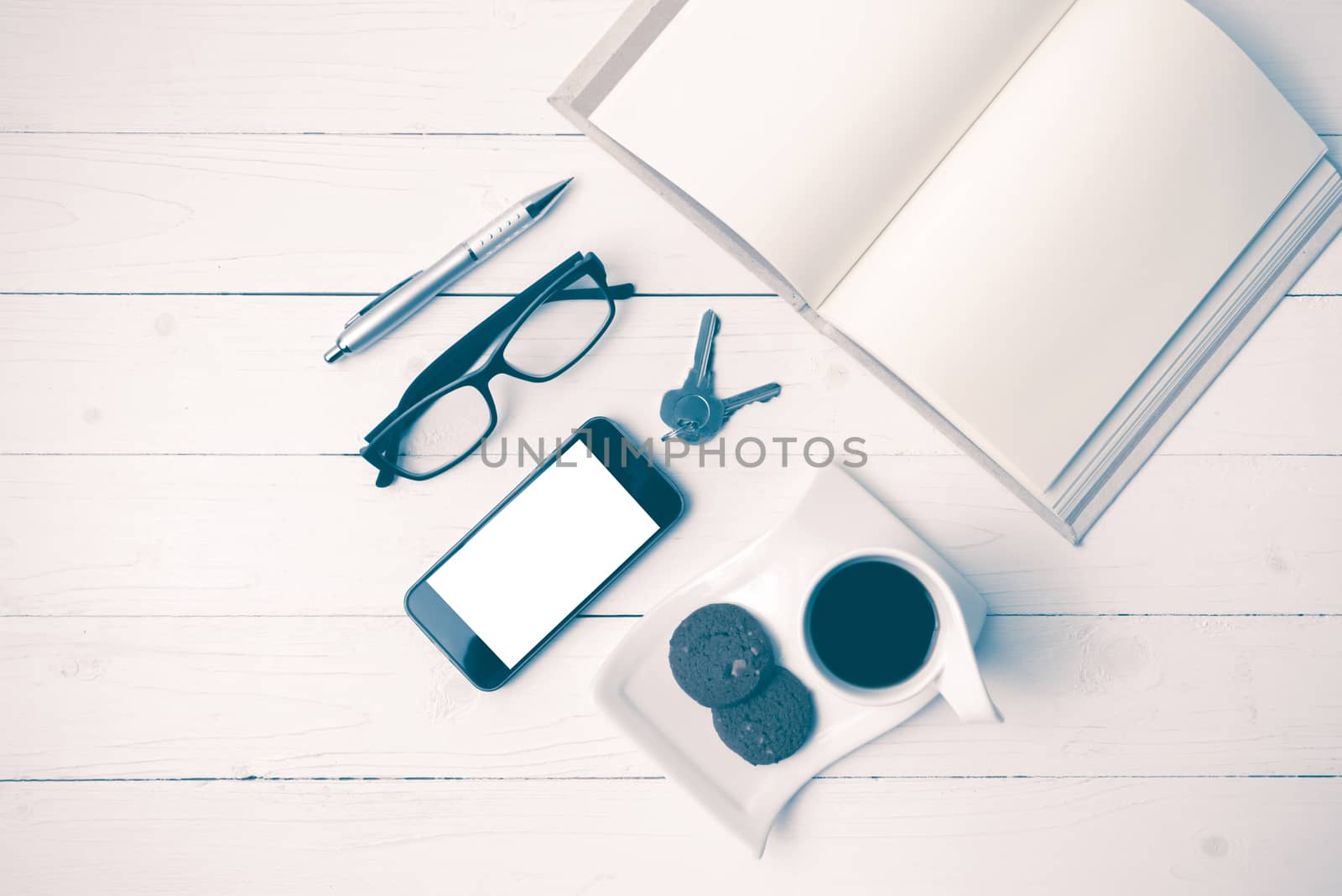 coffee cup with cookie,phone,open notebook and eyeglasses on white wood table vintage style