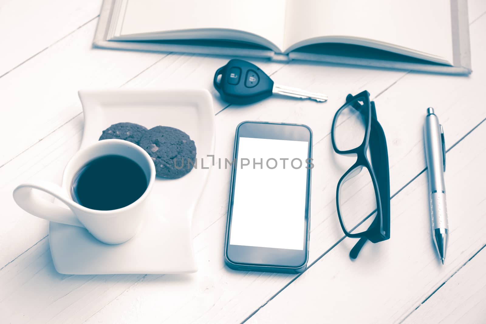coffee cup with cookie,phone,open notebook,car key and eyeglasses on white wood table vintage style