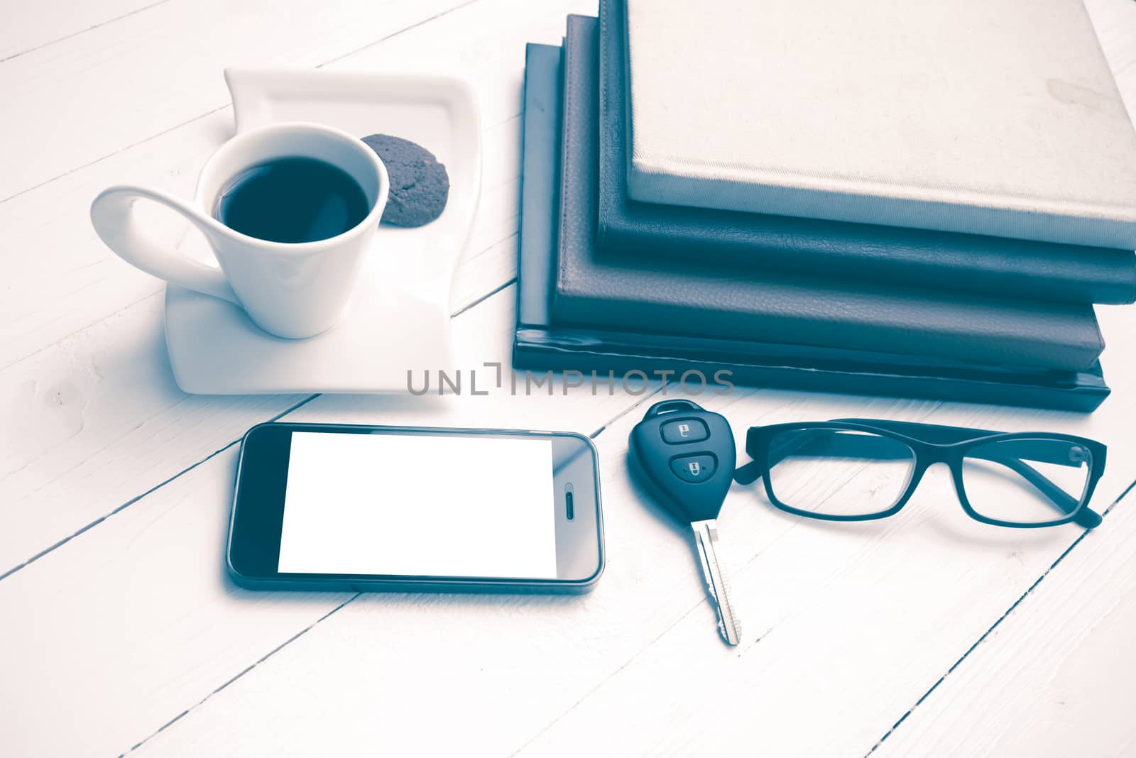 coffee cup with cookie,phone,stack of book and car key on white wood table vintage style