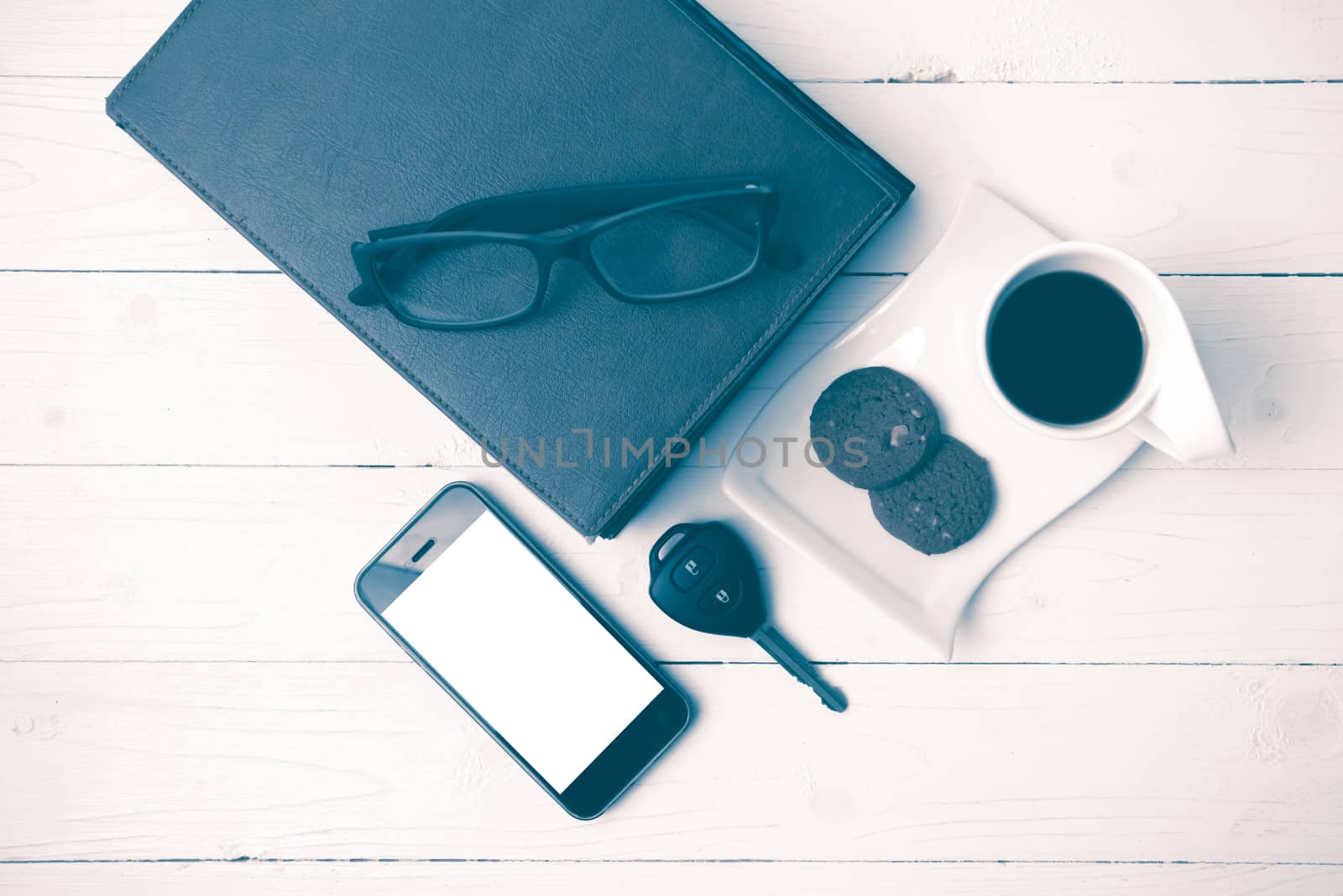 coffee cup with cookie,phone,stack of book and car key on white wood table vintage style