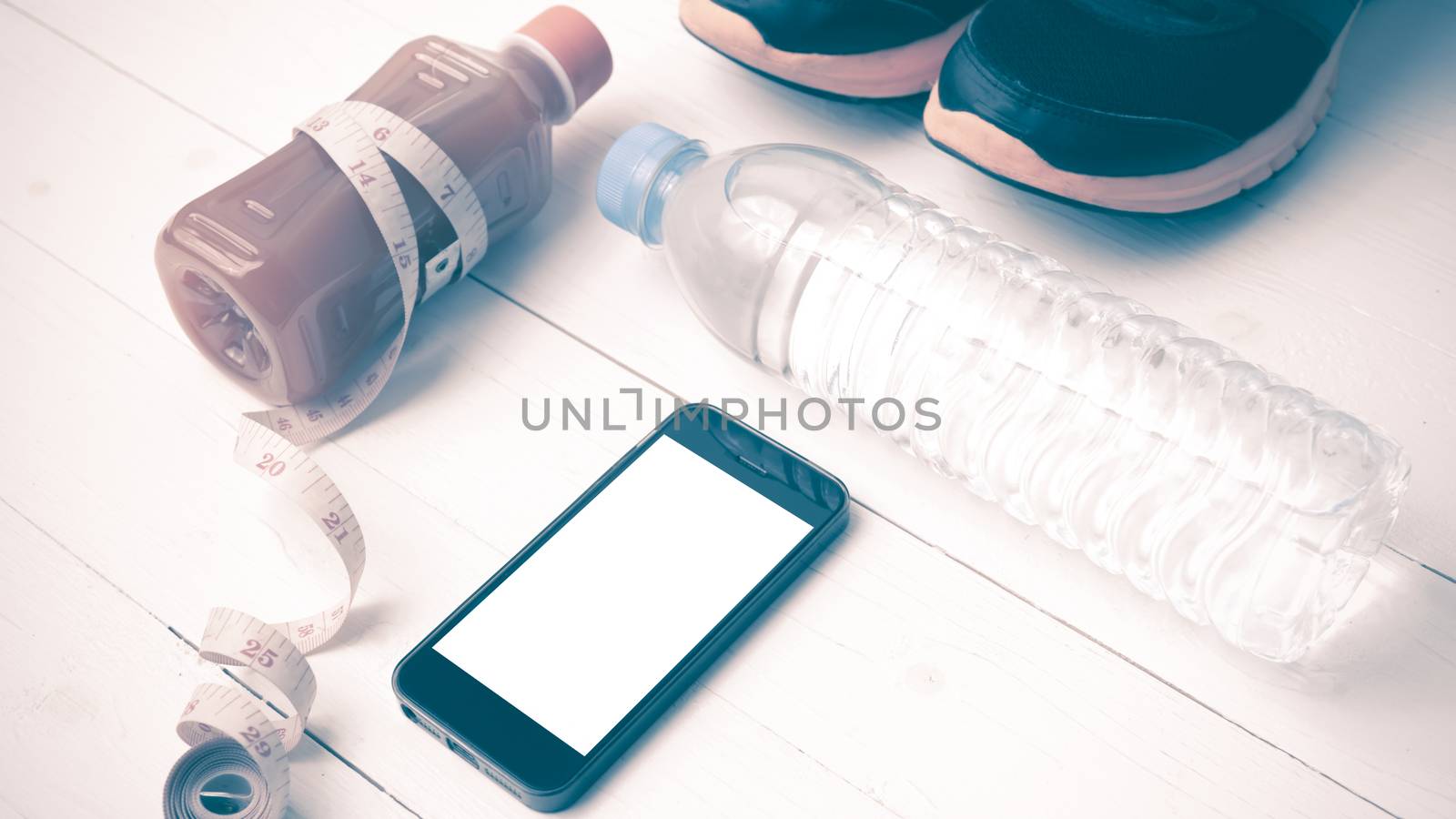 fitness equipment:running shoes,measuring tape,water,juice and phone on white wood background vintage style