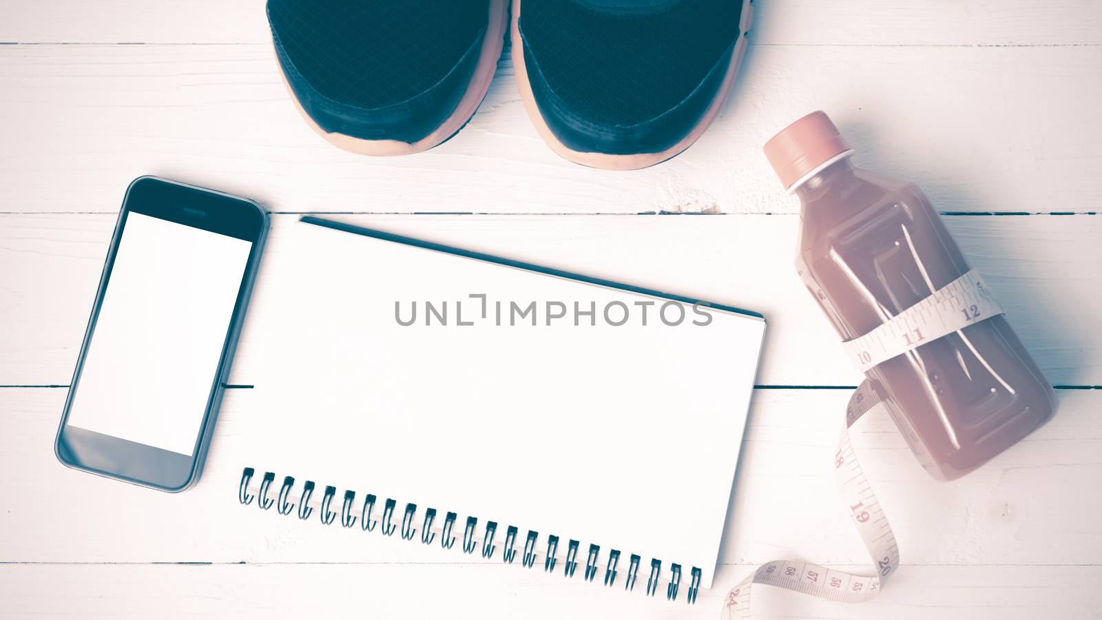 fitness equipment:running shoes,juice,measuring tape,notepad and phone on white wood background vintage style