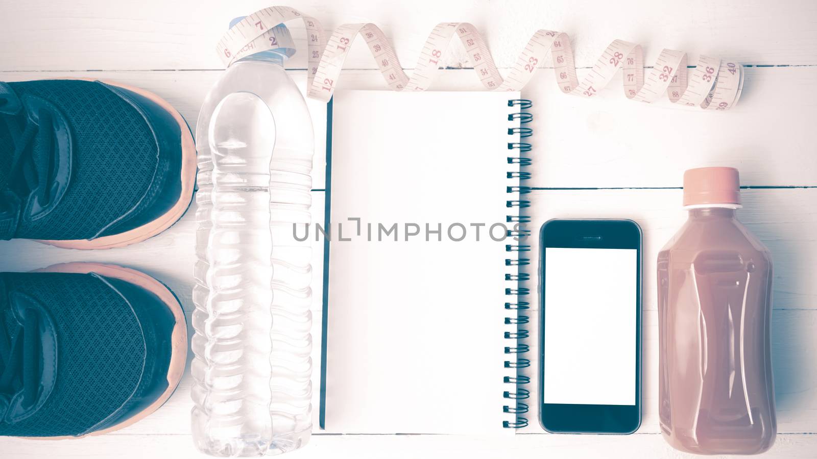 fitness equipment:running shoes,water,measuring tape,notepad,phone and juice on white wood background vintage style