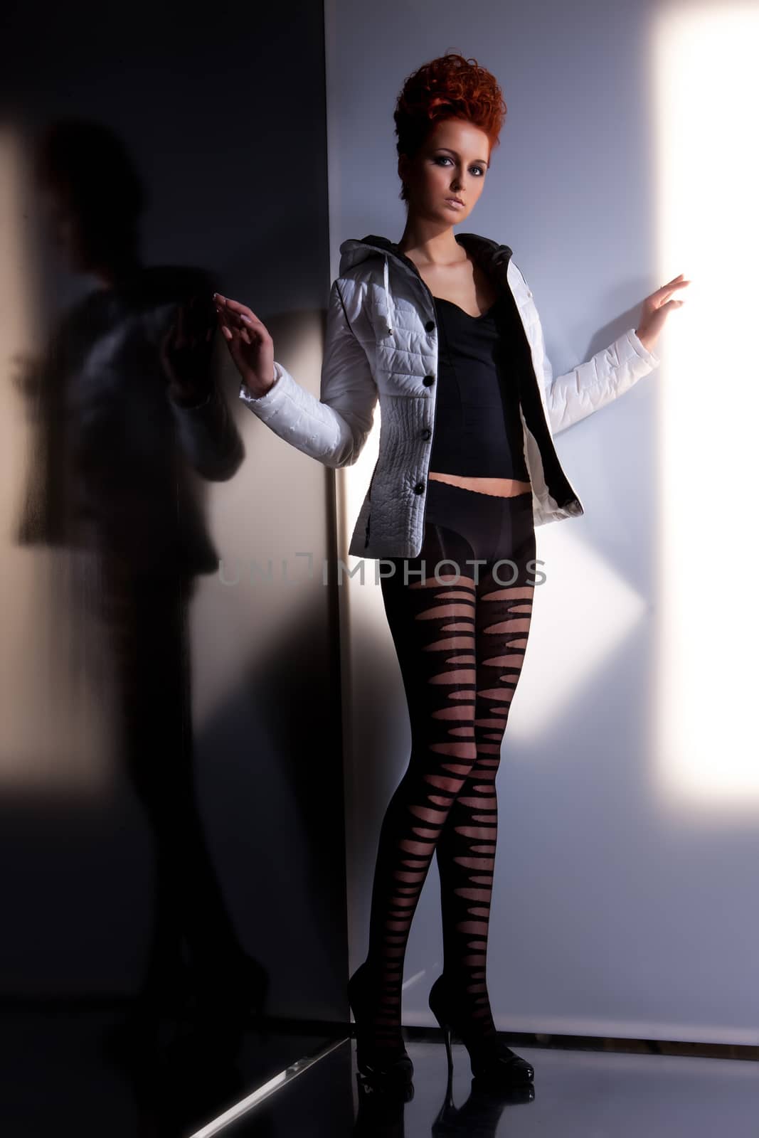 Young beautiful woman in fashionable clothing on isolated studio background