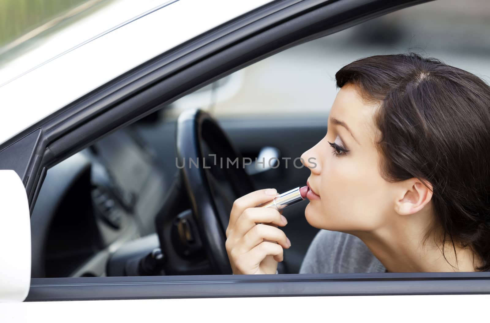 Pretty young woman in a car doing makeup by Nobilior