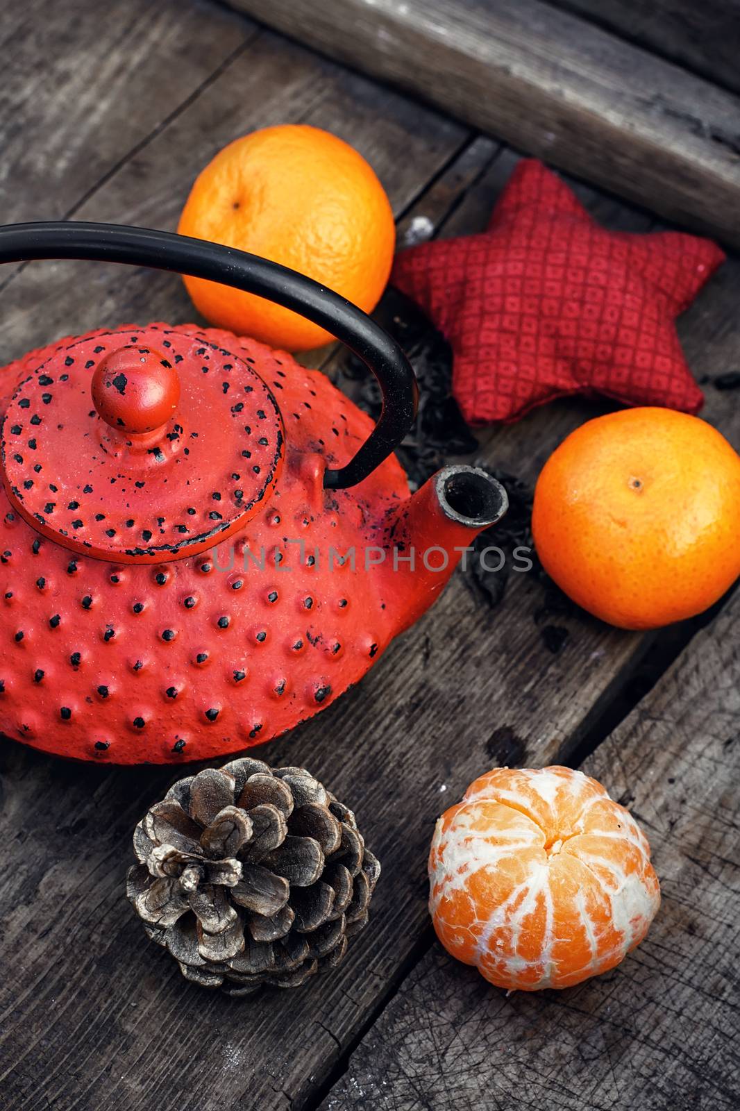 Red cast iron teapot,tangerine,bump and toy on wooden background