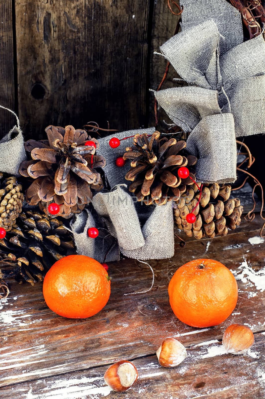 Woven Christmas wreath decorated with cones on background of ripe tangerines
