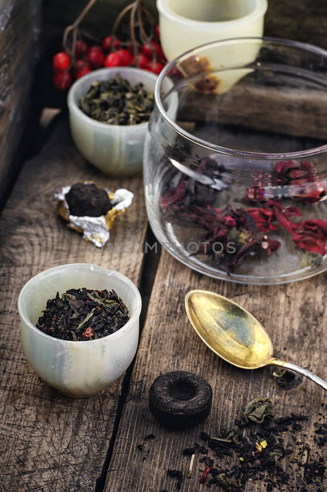 small cup with tea brewing in the background spoons and viburnum