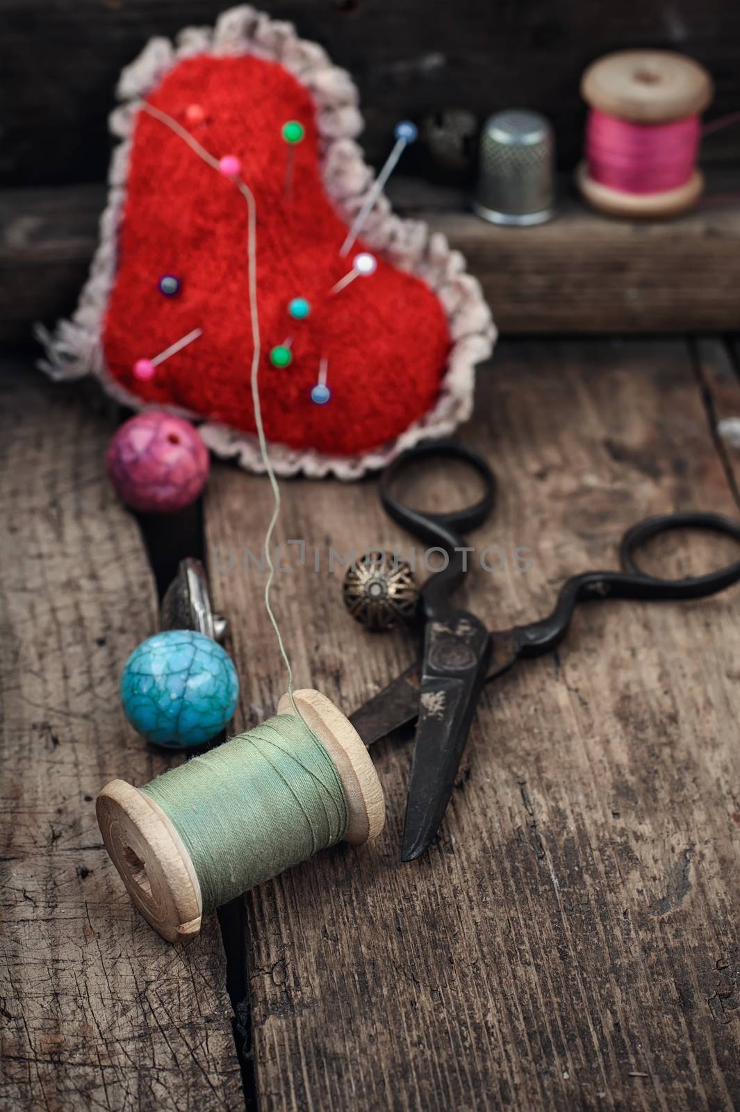 Old scissors,spools of thread,buttons and beads on wooden table