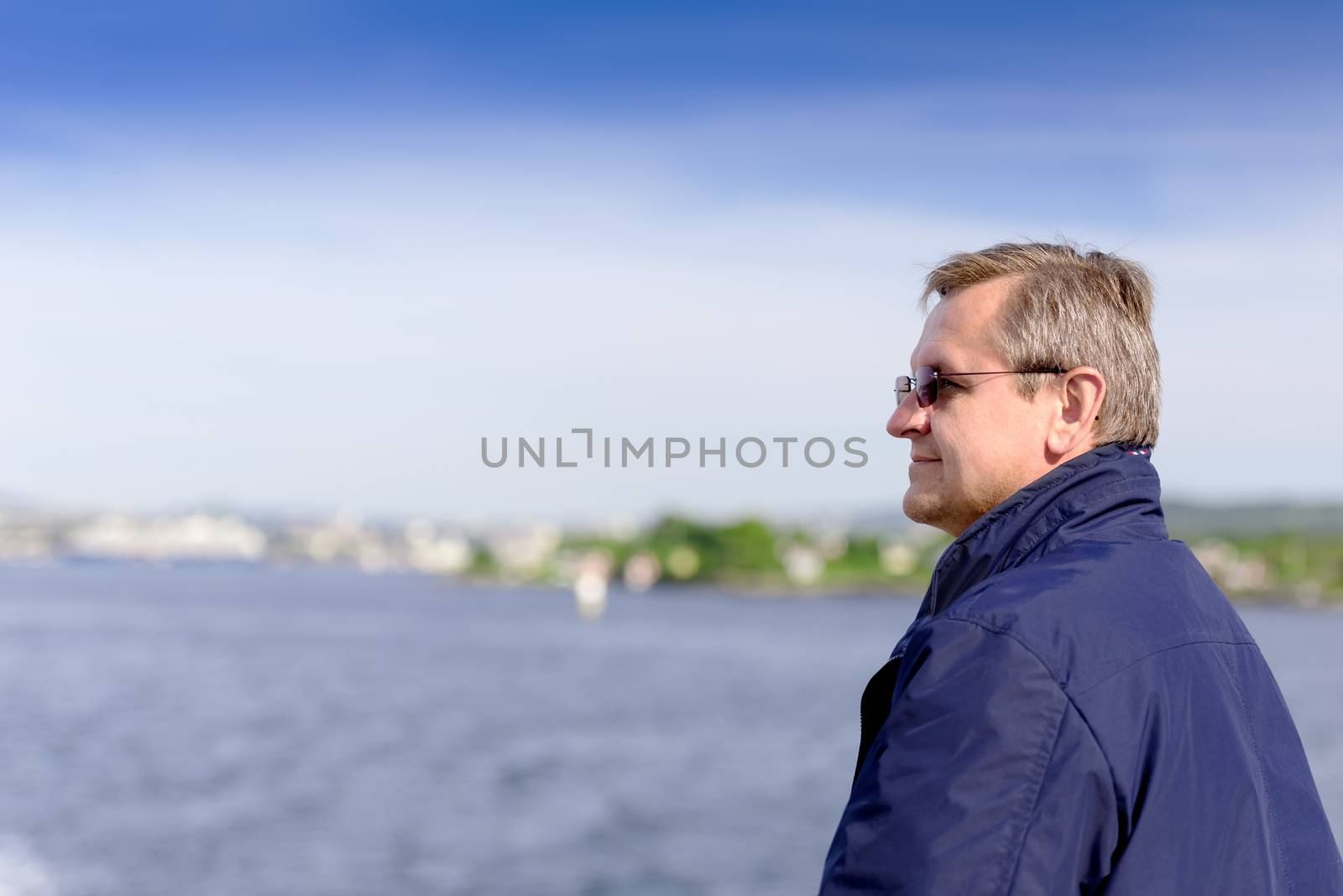 Closeup of smiling mature man looking away with fjord in background