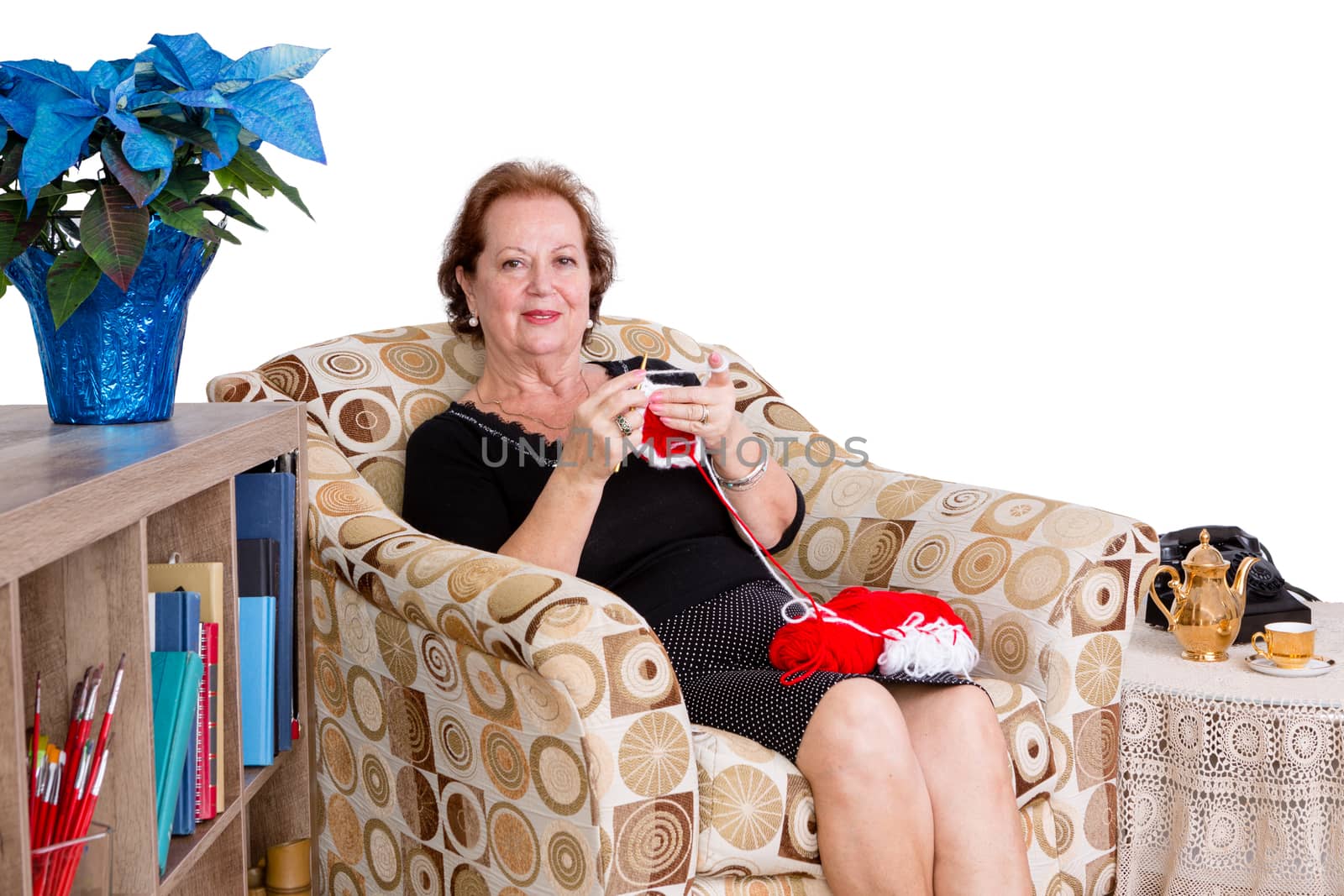 Elegant elderly lady sitting knitting at home by coskun