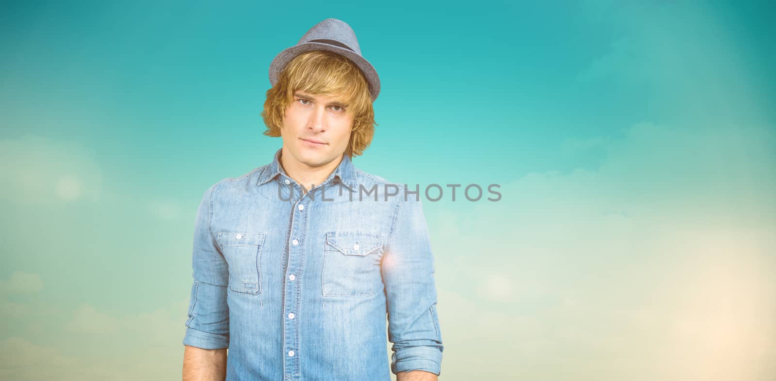 Serious blond hipster staring at camera against blue green background