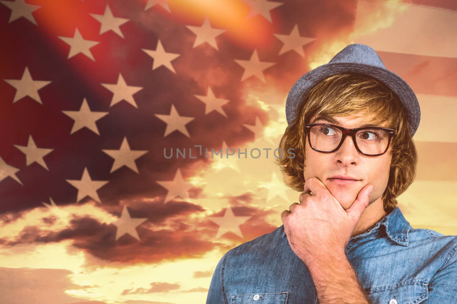 Close up of hipster man thinking against american flag rippling over grassy landscape