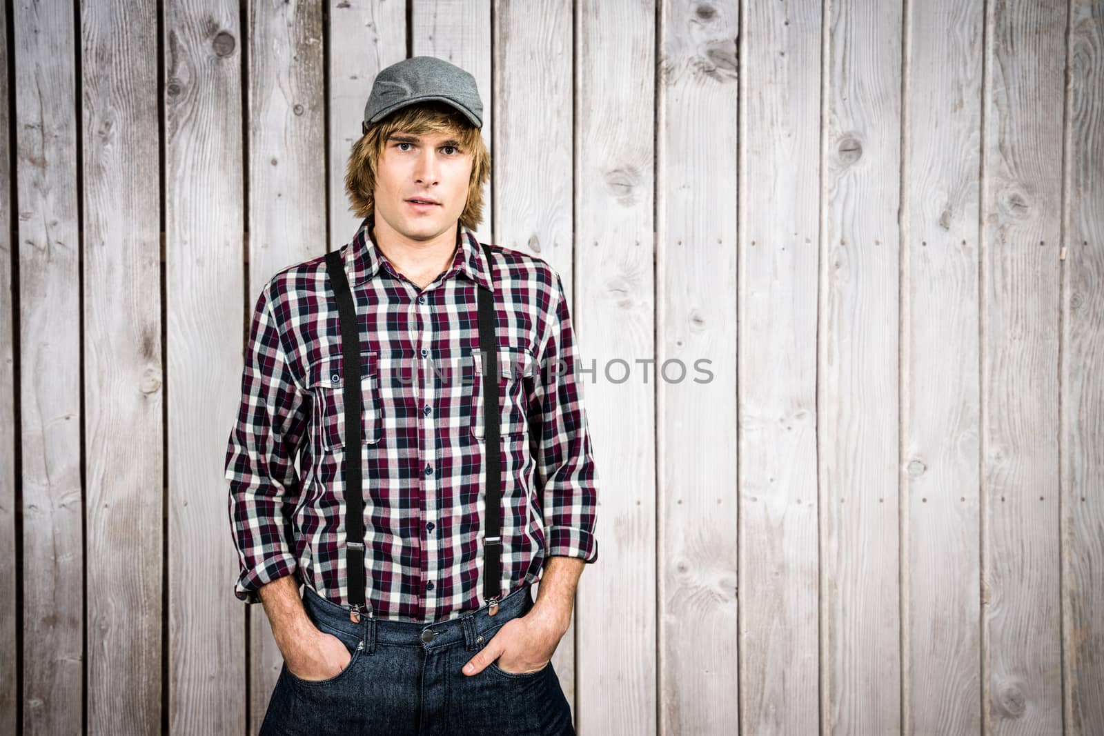 Serious blond hipster staring at camera against wooden planks