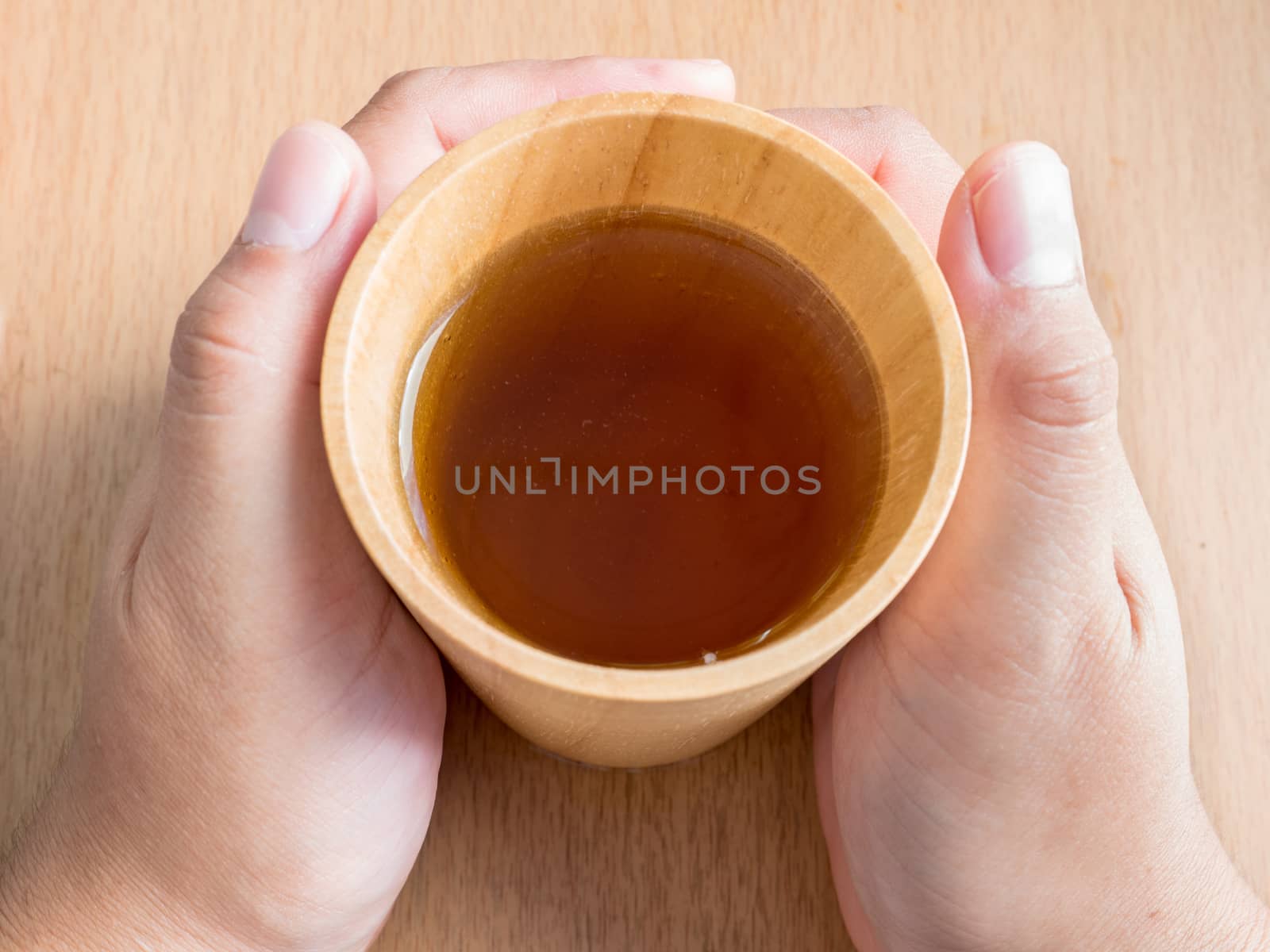 Closeup of female hands holding wood cup of Organic Jasmine Tea