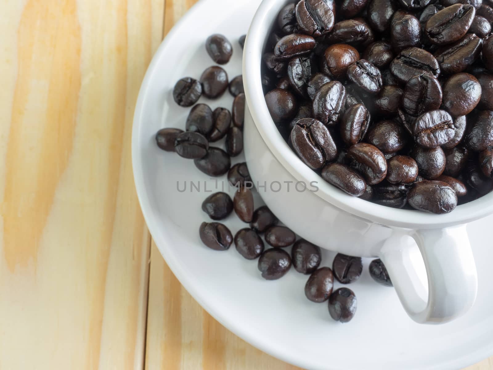 Roasted coffee beans in pretty white cup on wooden table