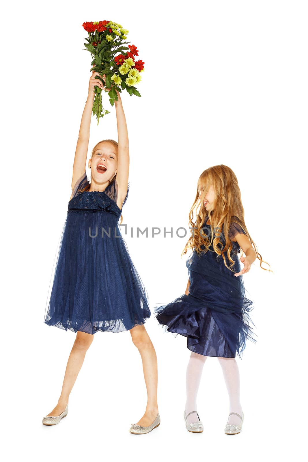 Two charming little girls in a blue dresses with a bouquet of flowers