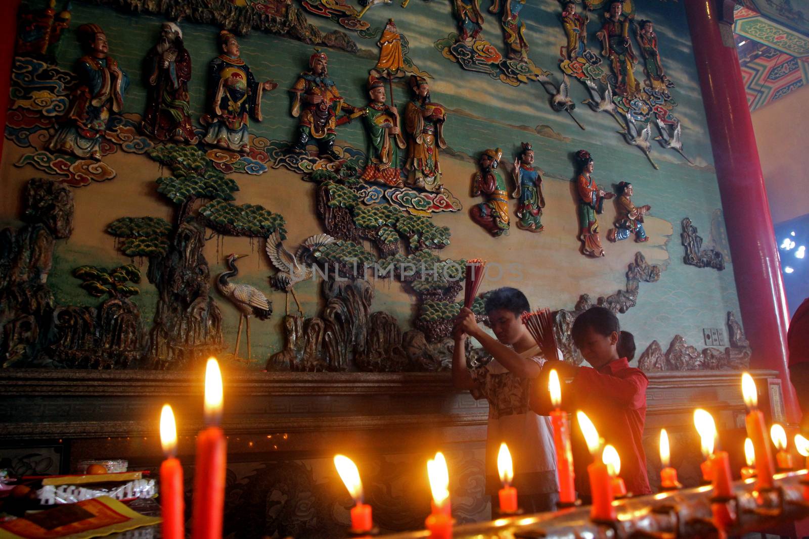 INDONESIA, Kuta: Children light candles and pray as they celebrate the Lunar New Year at a temple in Kuta, Bali, Indonesia on February 8, 2016. Others perform traditional dance and burn incense as they welcome the Year of the Monkey.