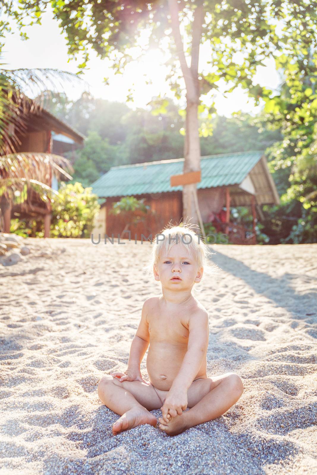 Little angel sitting on a white sand beach in Thailand