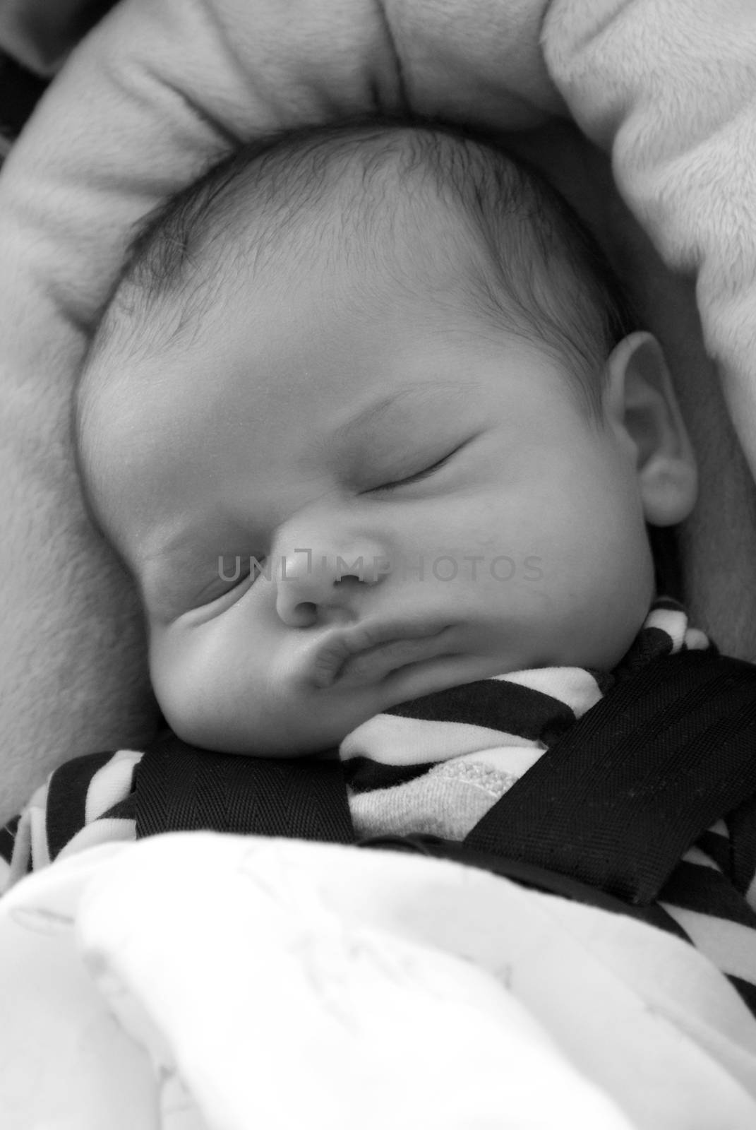 A newborn baby boy sleeps in his carseat.