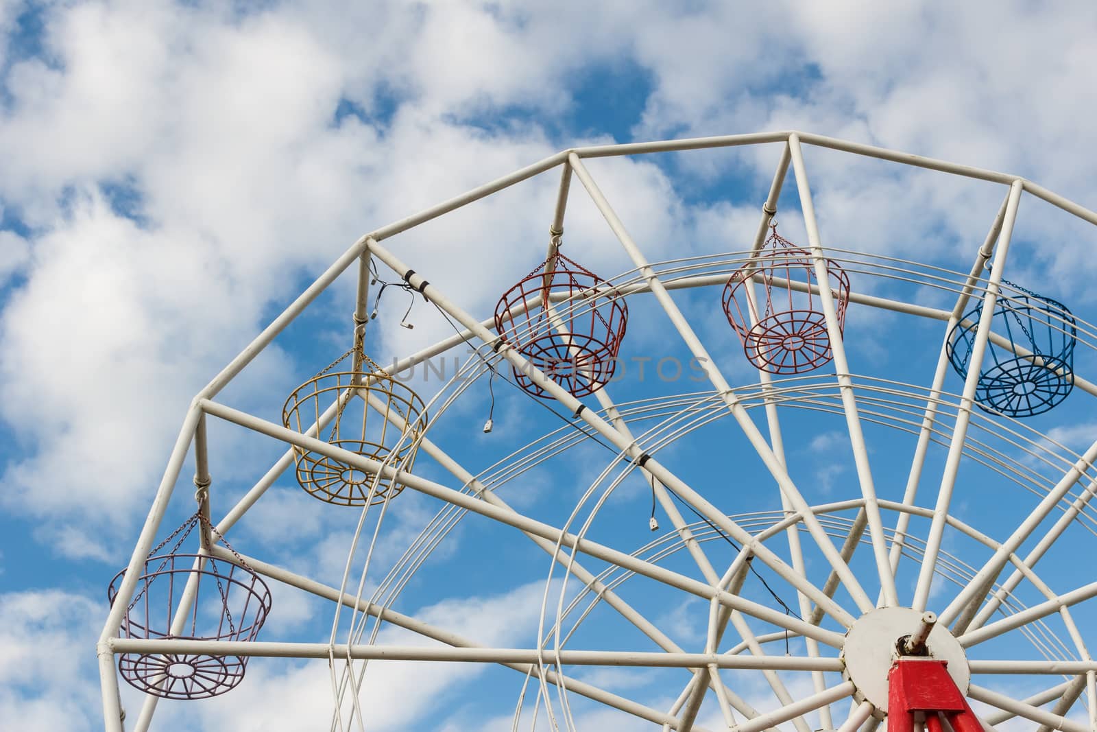 Part of Ferris wheel with blue sky in background.