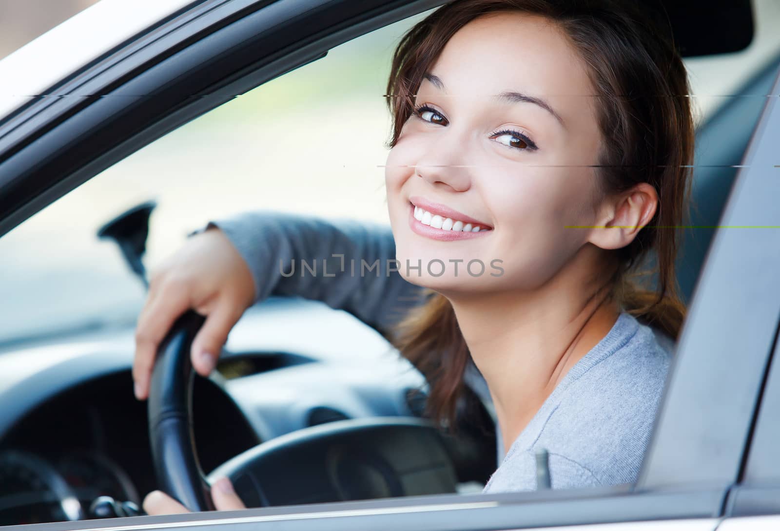 Pretty girl in a car smiling to you